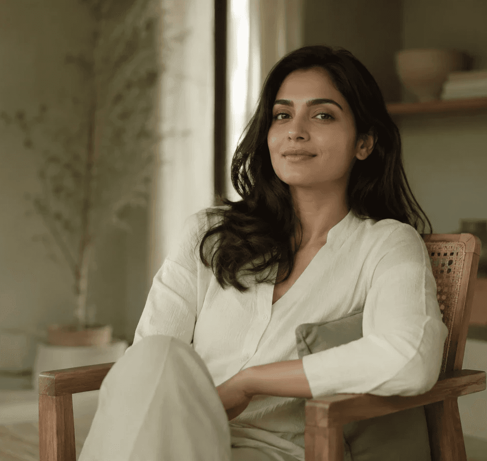 A woman relaxing in a wooden chair by a window in a calm, softly lit room