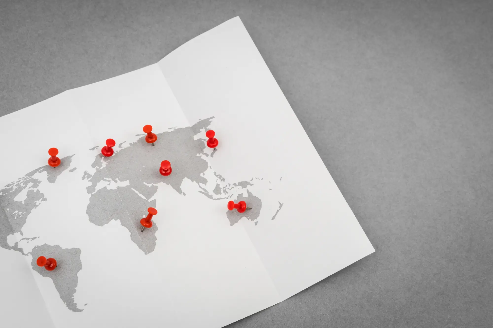 Dünya haritası üzerinde kırmızı raptiyelerle işaretlenmiş küresel lokasyonlar.