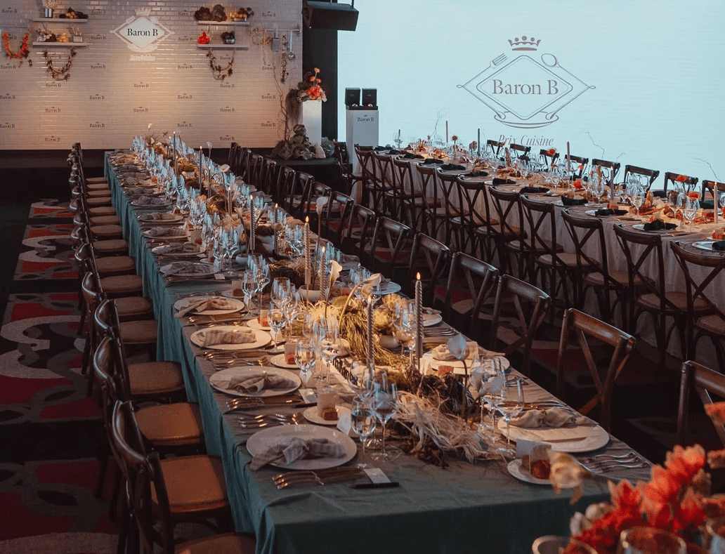 Arreglo floral con hortensias verdes, repollos y amaranto rojo colgante sobre una chimenea de mármol ornamentada, con un espejo dorado de fondo