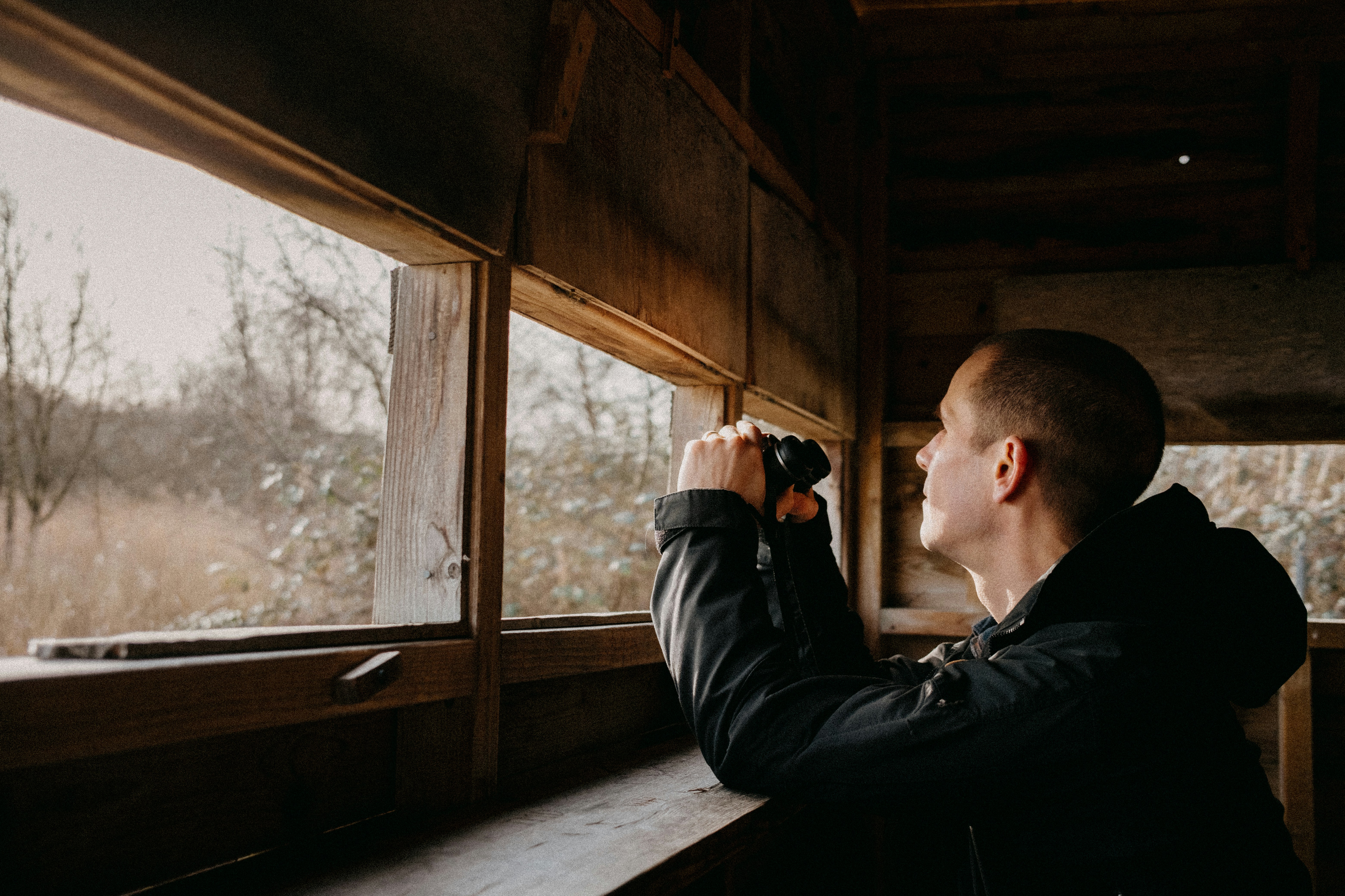 a man looking out of a window in a cabin