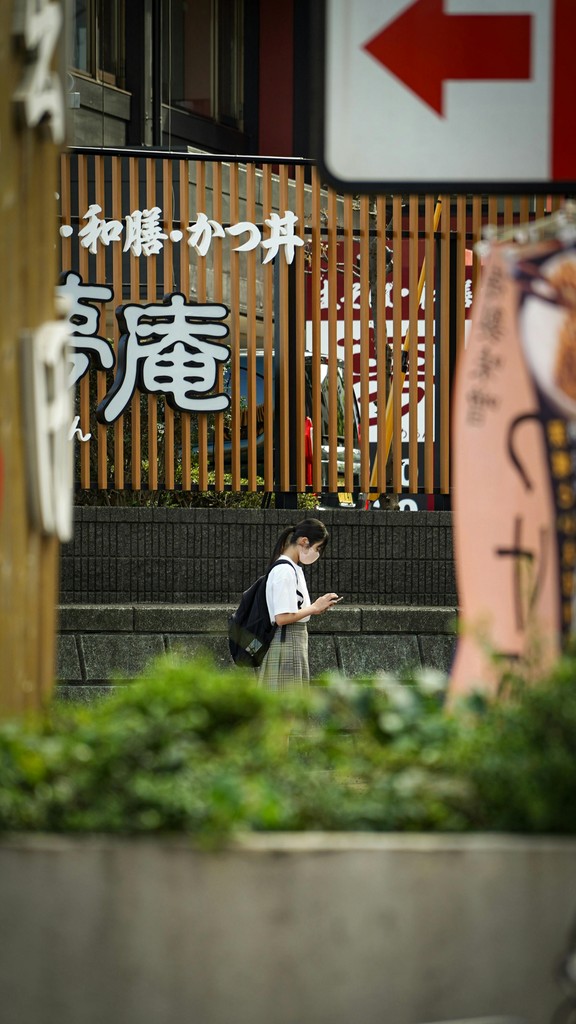 Young women walking past japanese storefront
