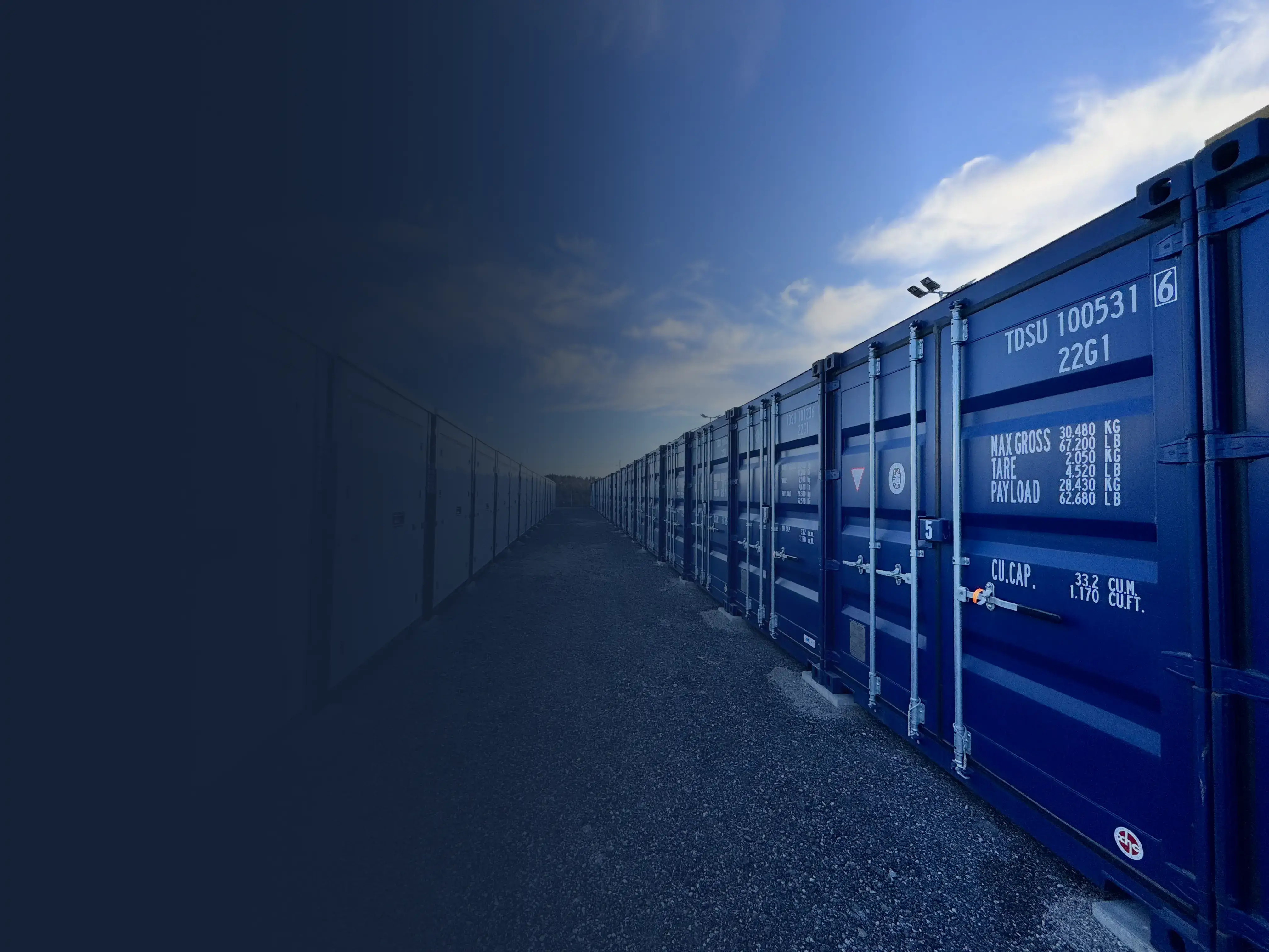 Walkway between white and blue container storage outdoors under blue sky