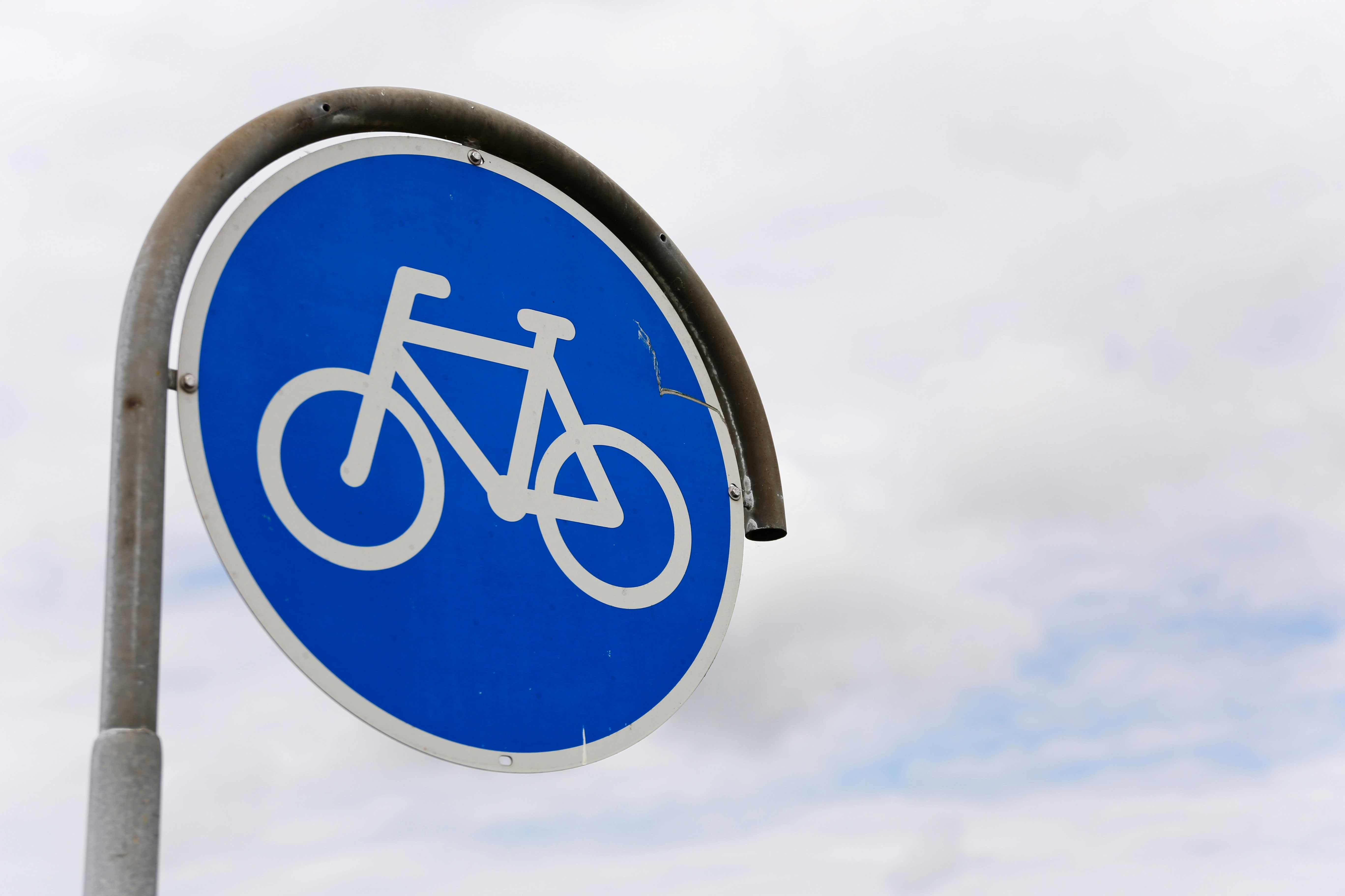 Blue bicycle lane sign along a city street.
