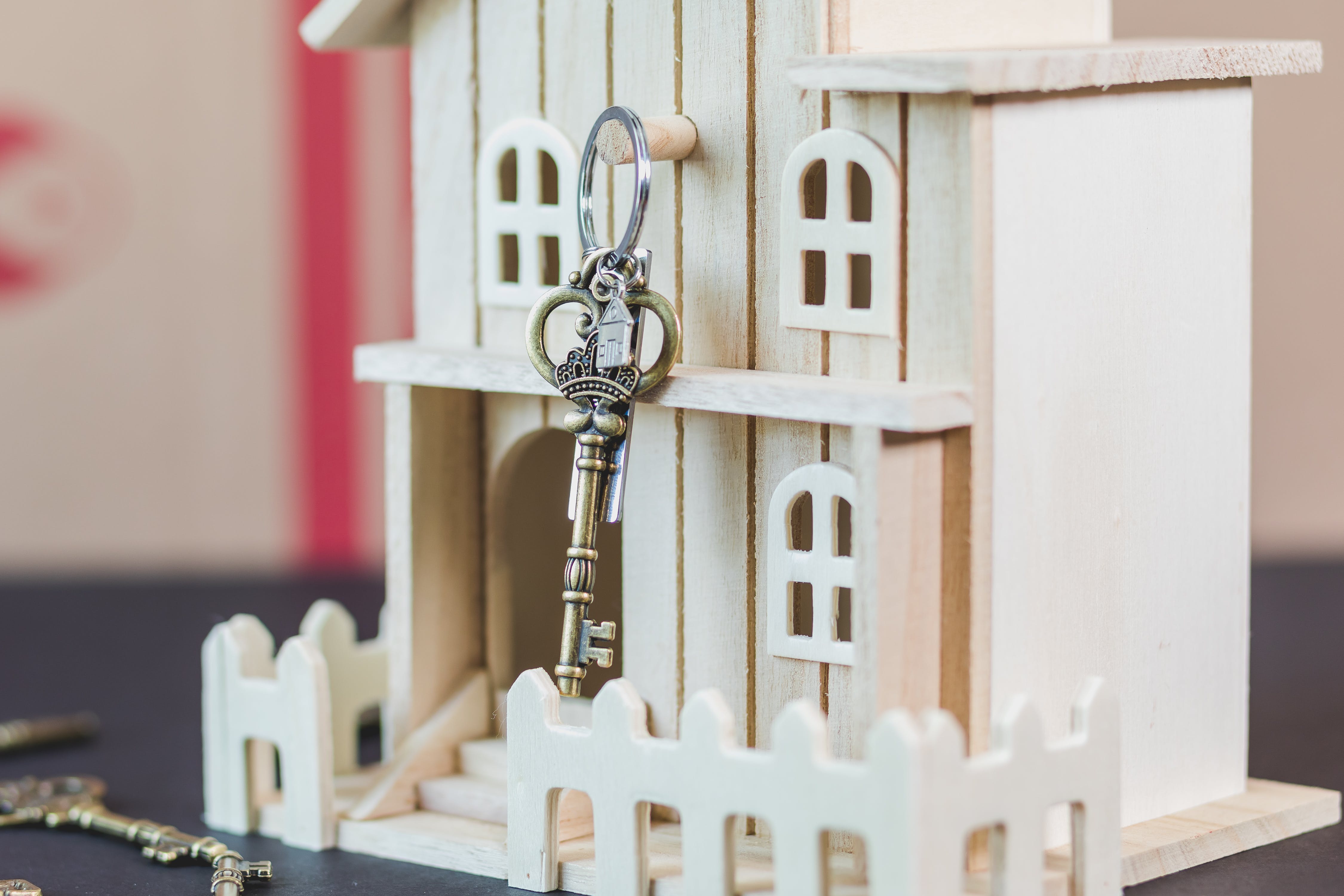 Mortgage house key hanging on a wooden doll house