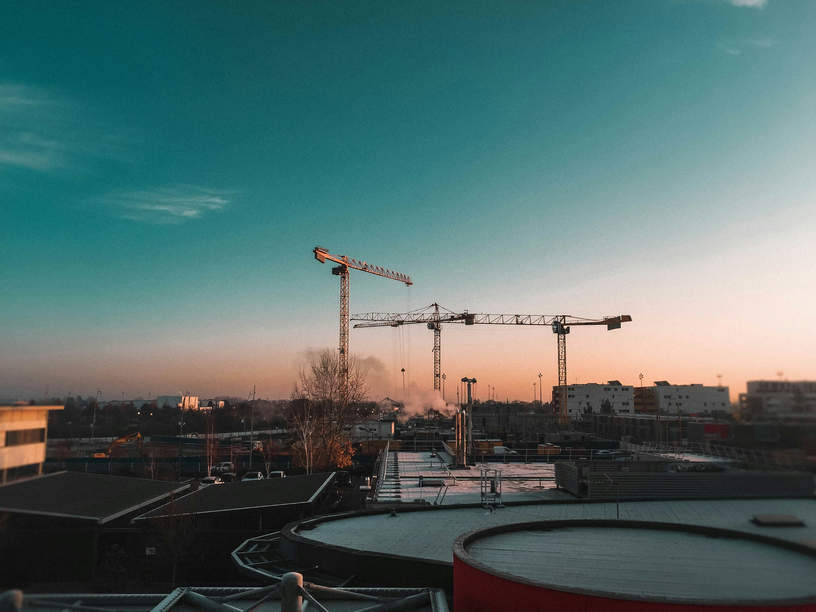 buildings and tower cranes under blue sky