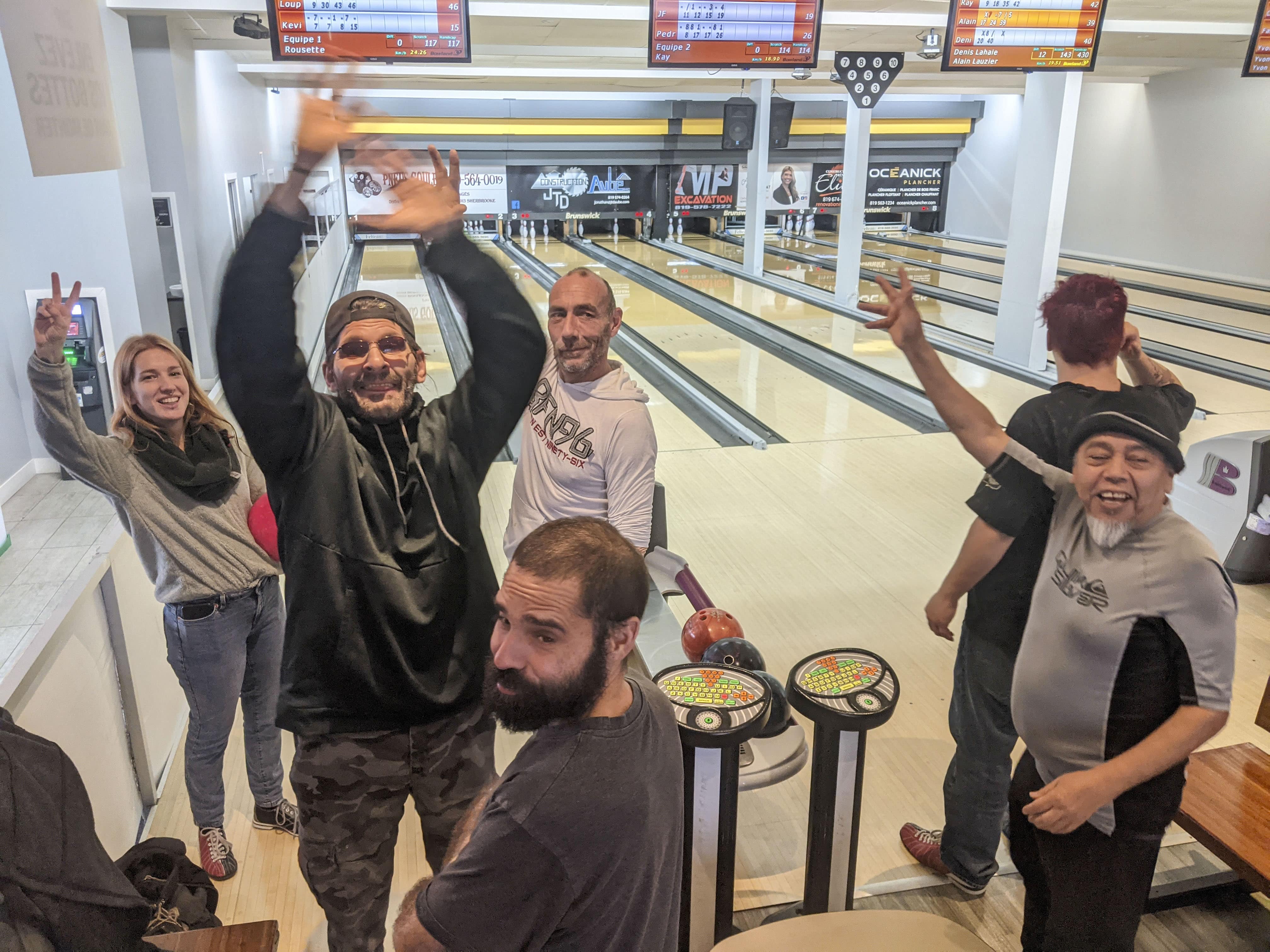 Groupe de personnes dans un métro ou train, l’une levant les bras en souriant, ambiance festive et solidaire.