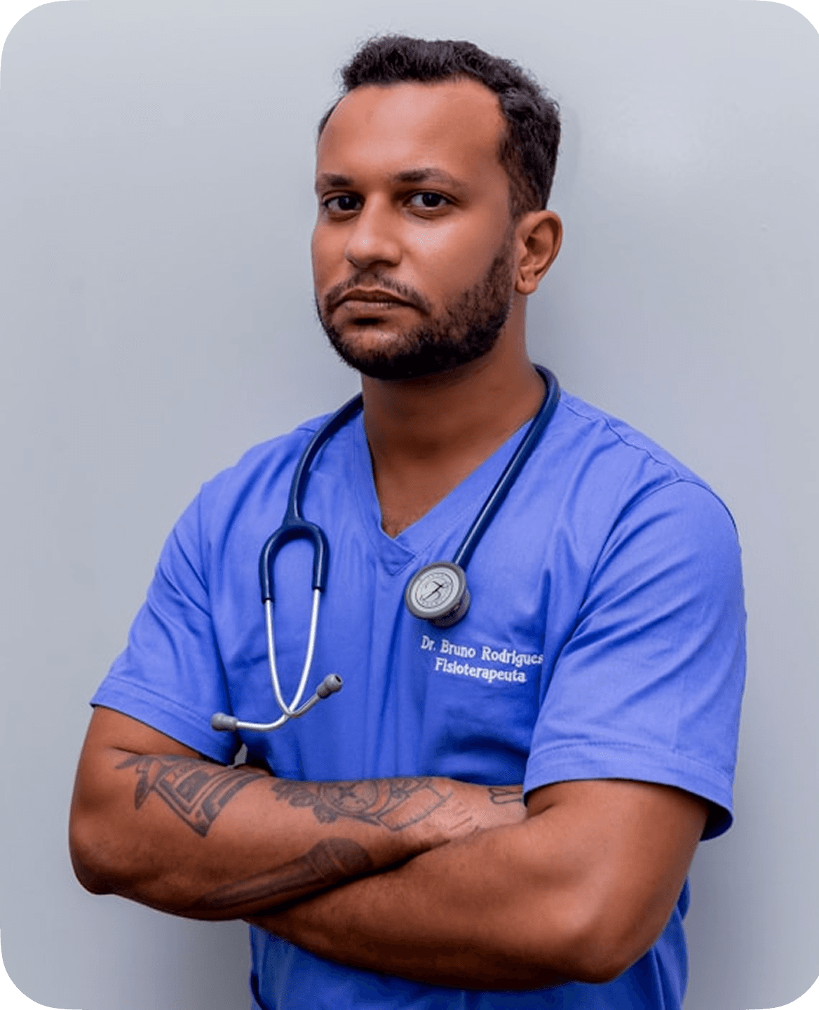 A healthcare professional wearing a blue medical scrub and stethoscope stands confidently with crossed arms against a neutral background.