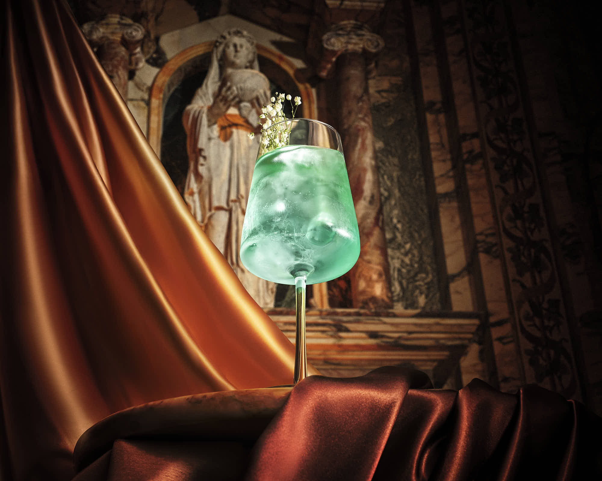 Elegant teal cocktail with floral garnish on luxurious bronze fabric backdrop.