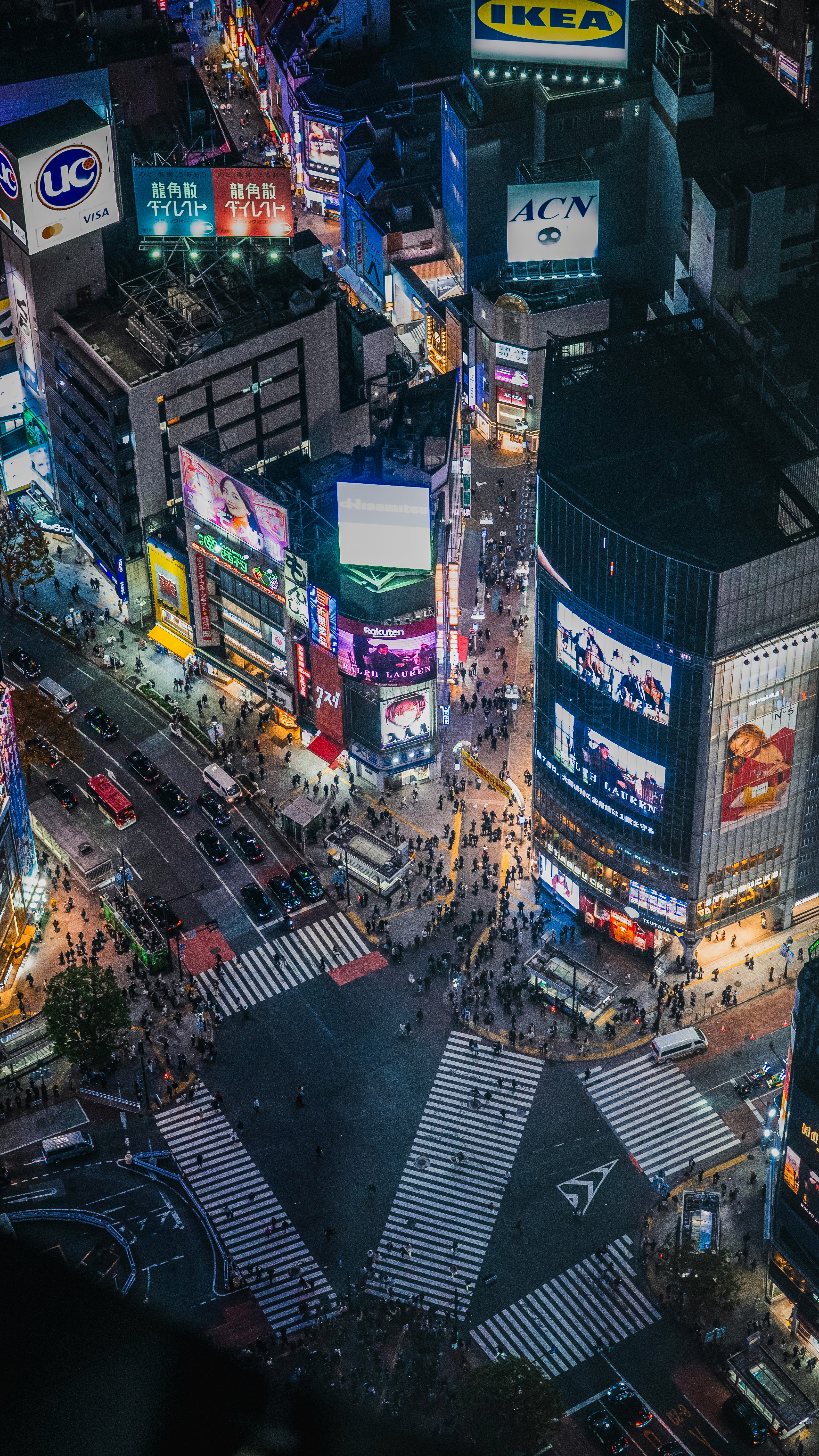 Busy city intersection at night with glowing signs.