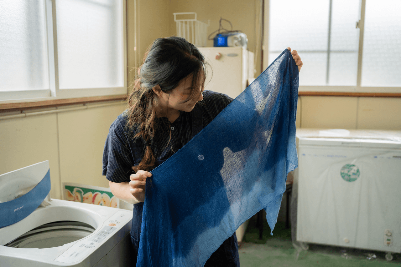 Girl holding up a scarf which has been indigo dyed