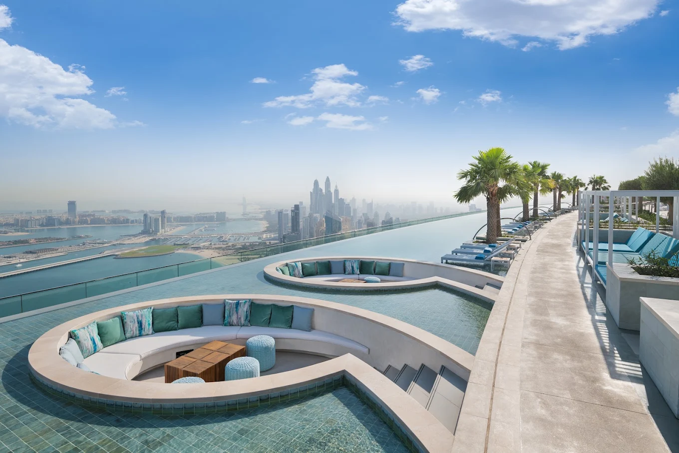 Infinity-Pool mit Blick auf die Skyline von Dubai und luxuriöse Sonnenliegen.