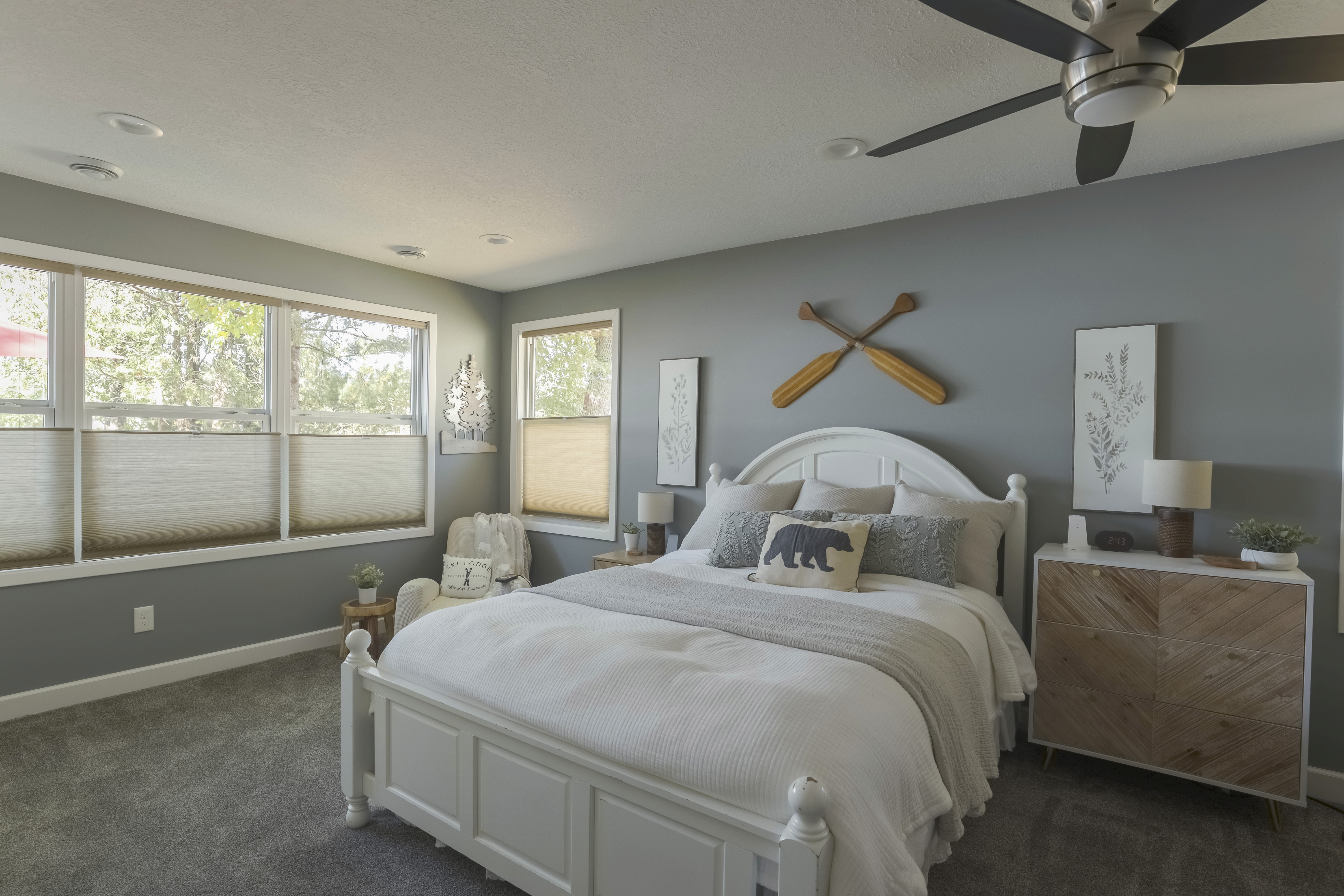 Bright bedroom layout with a gray accent wall and decorative wooden oars on the wall.