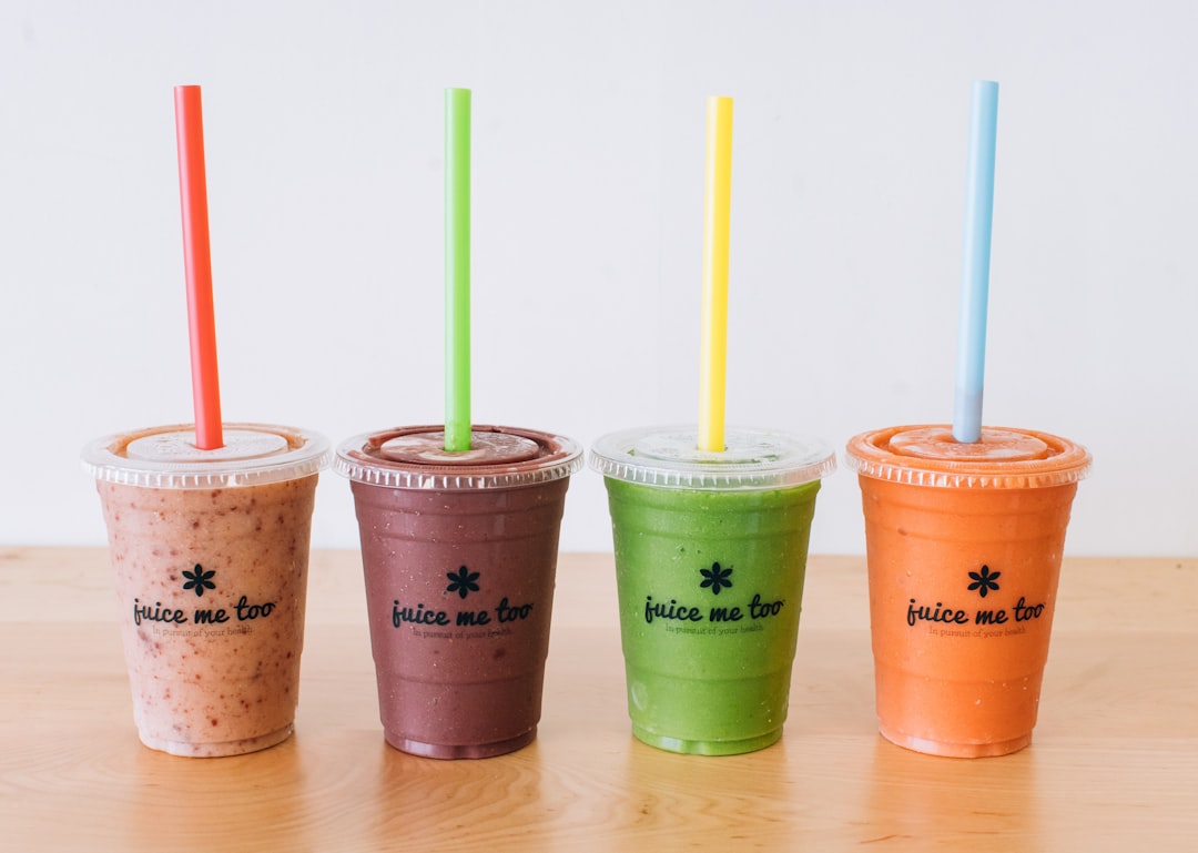 three cups of smoothie with straws on a table