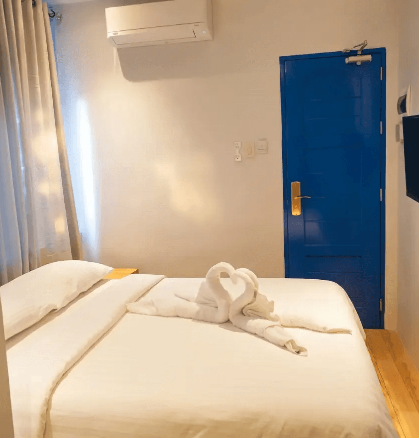 Cozy Double Room with glowing blue arched window and wooden bed at Oktowaves Hotel Nasugbu