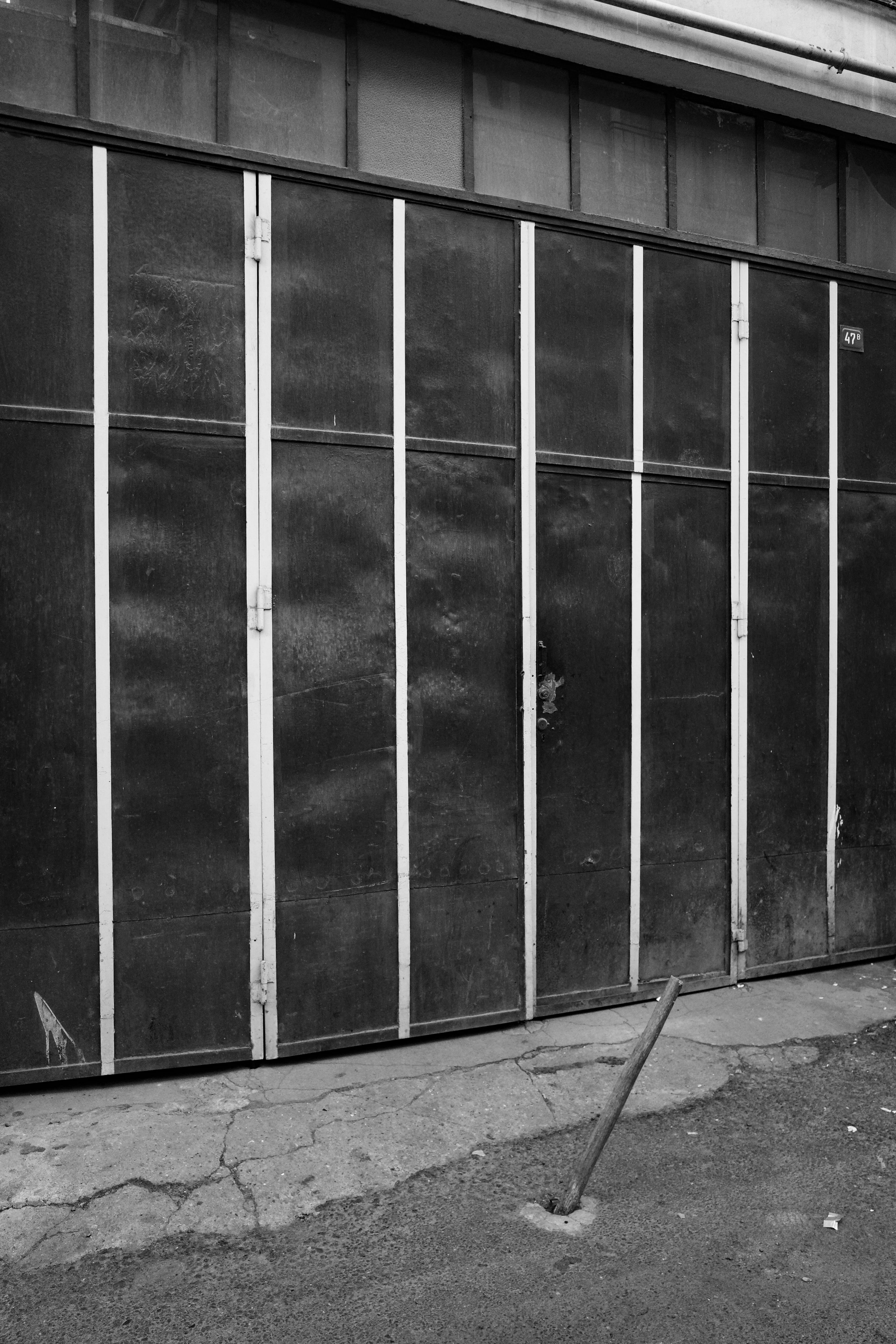 A black and white photo of a man leaning against a building