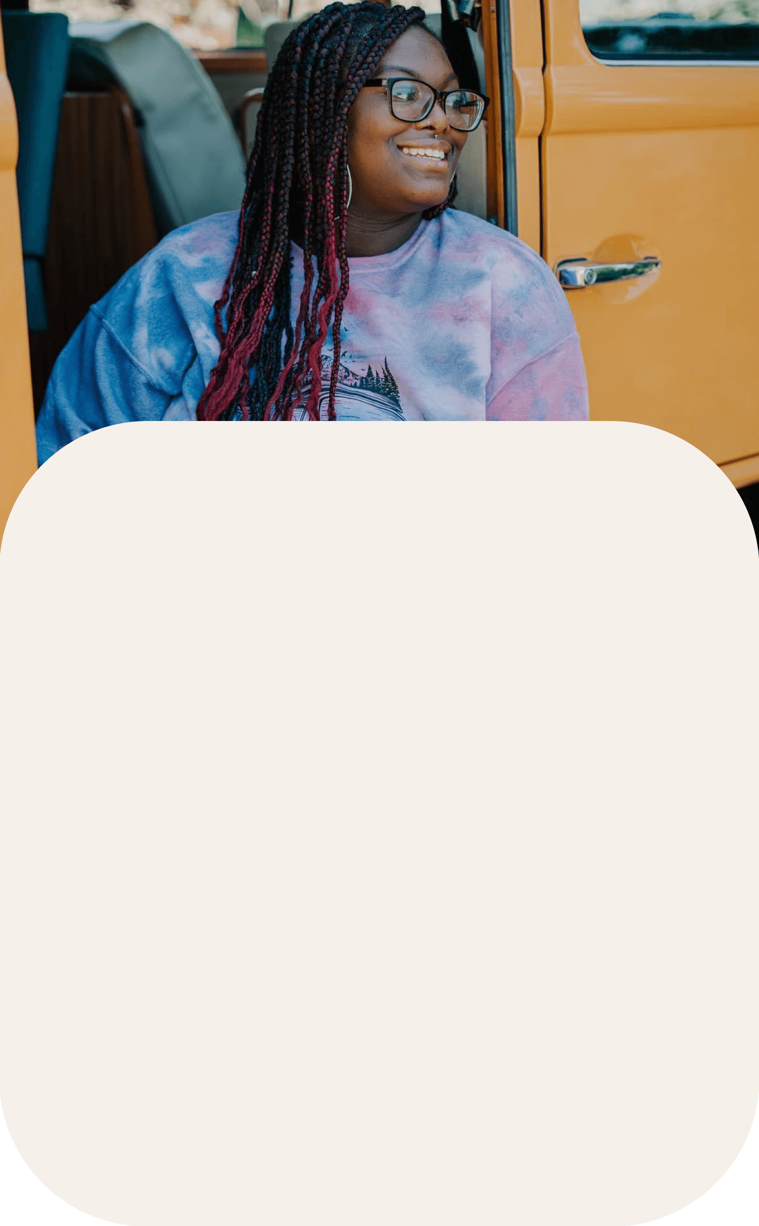 Women in tye-dye crewneck relaxing by her car.