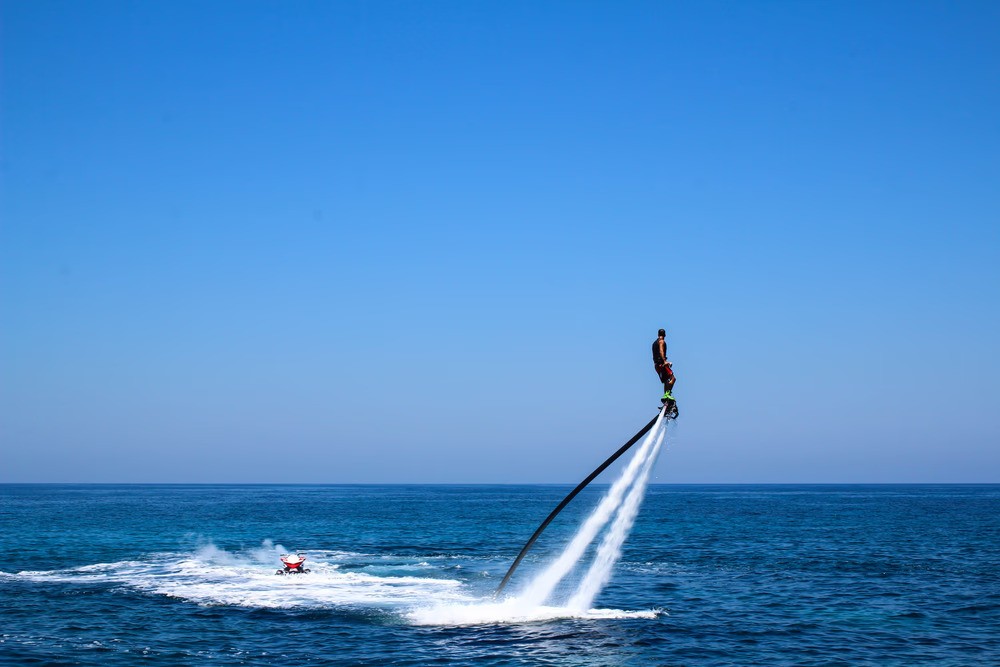 Person flyboarding high above the sea with Ride in Dubai on a clear sunny day.