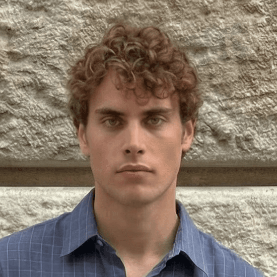a man with curly hair smiles at the camera