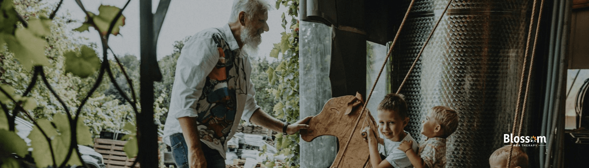 Older man pushing a wooden horse swing with three autistic young boys on it at home in Virginia.