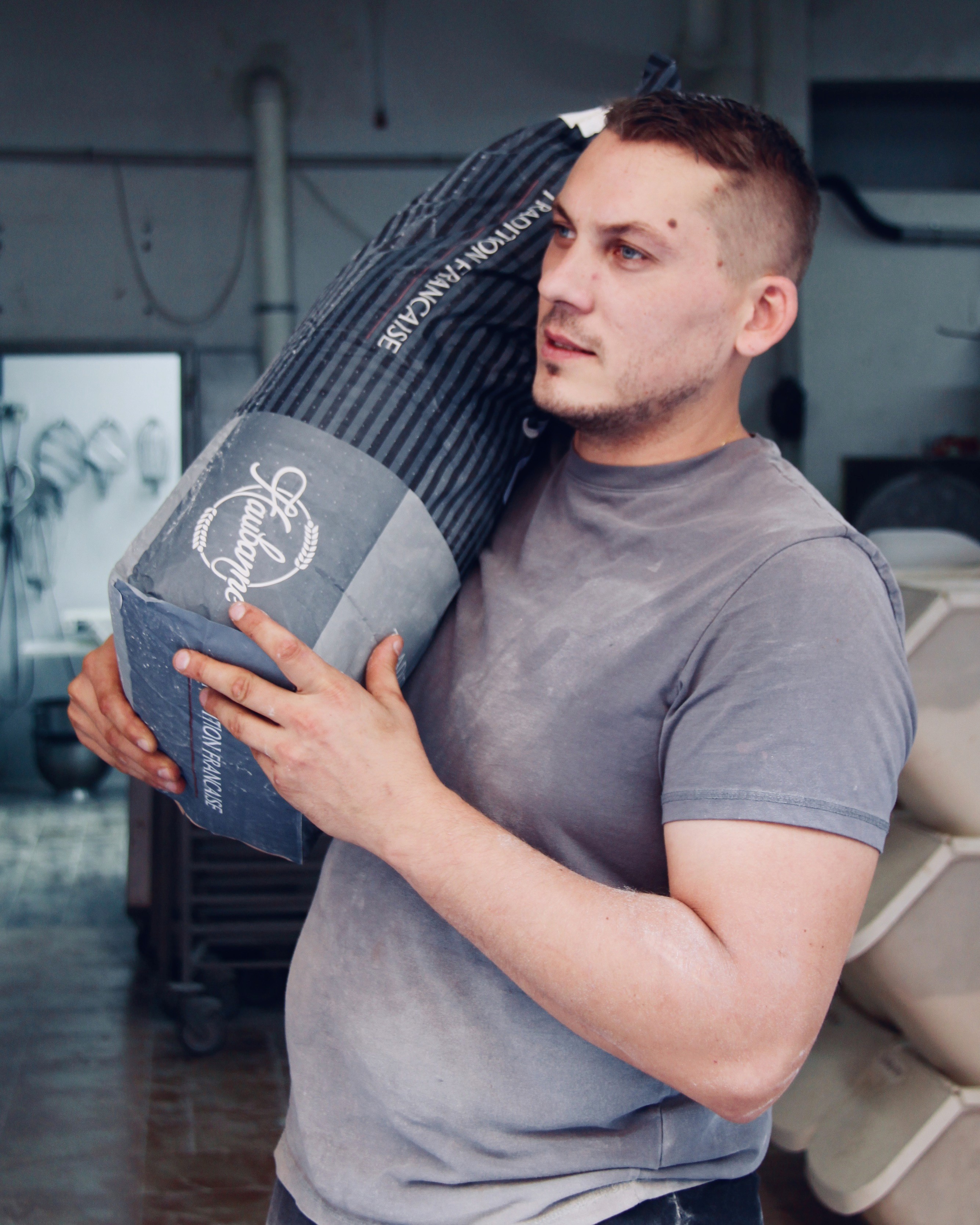 panadero pastelero frances cargando un saco de harina de tradicion francesa en obrador local en Denia