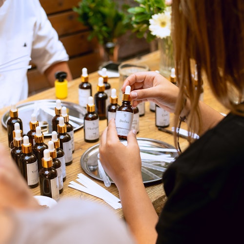 Mga kalahok sa isang talakayan sa mesa na pumipili ng mga sangkap mula sa iba't ibang bote ng pabango para gawing sarili nilang pabango.