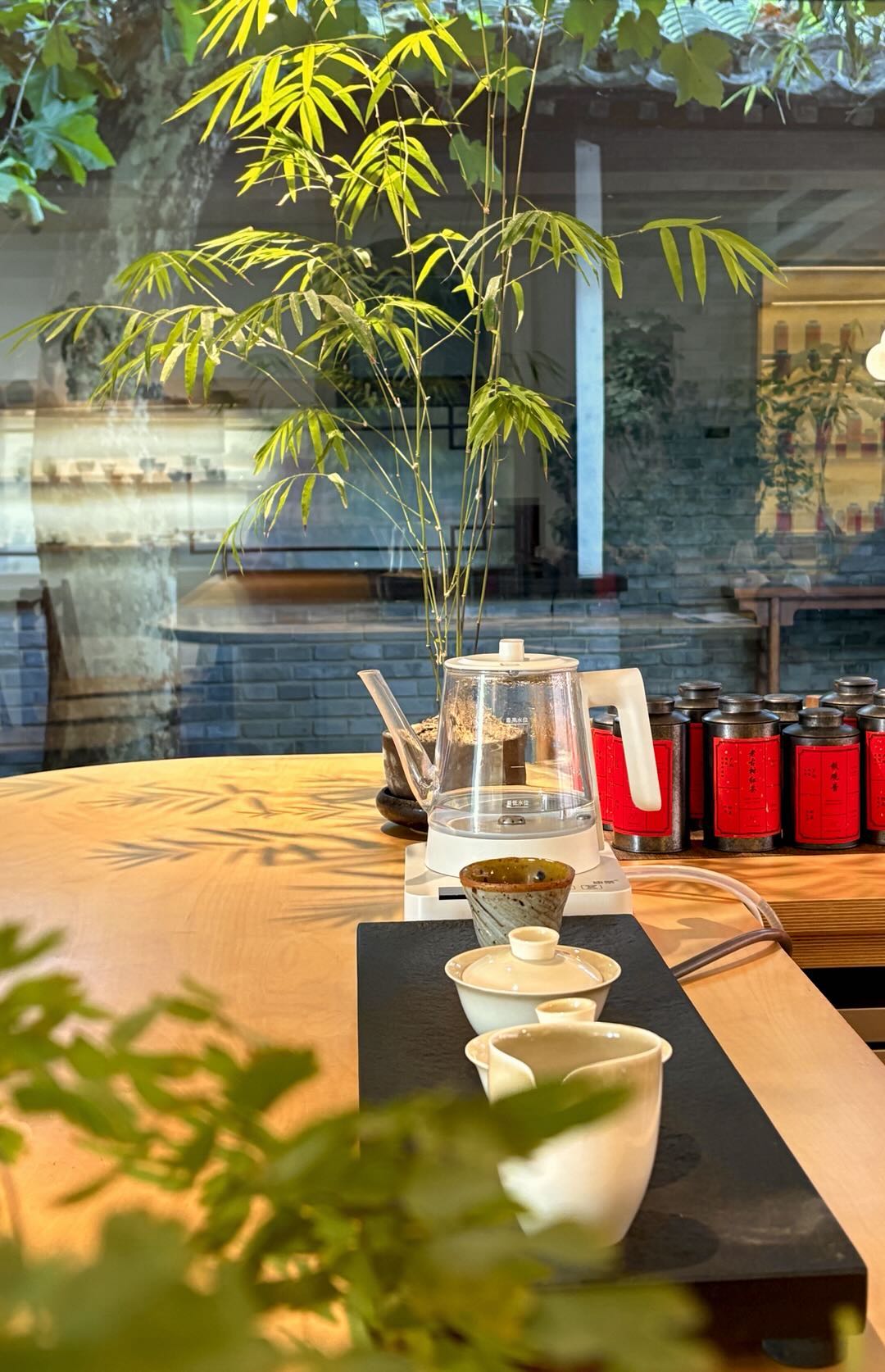 A tea table with a kettle, gaiwan, cups, and red tea tins