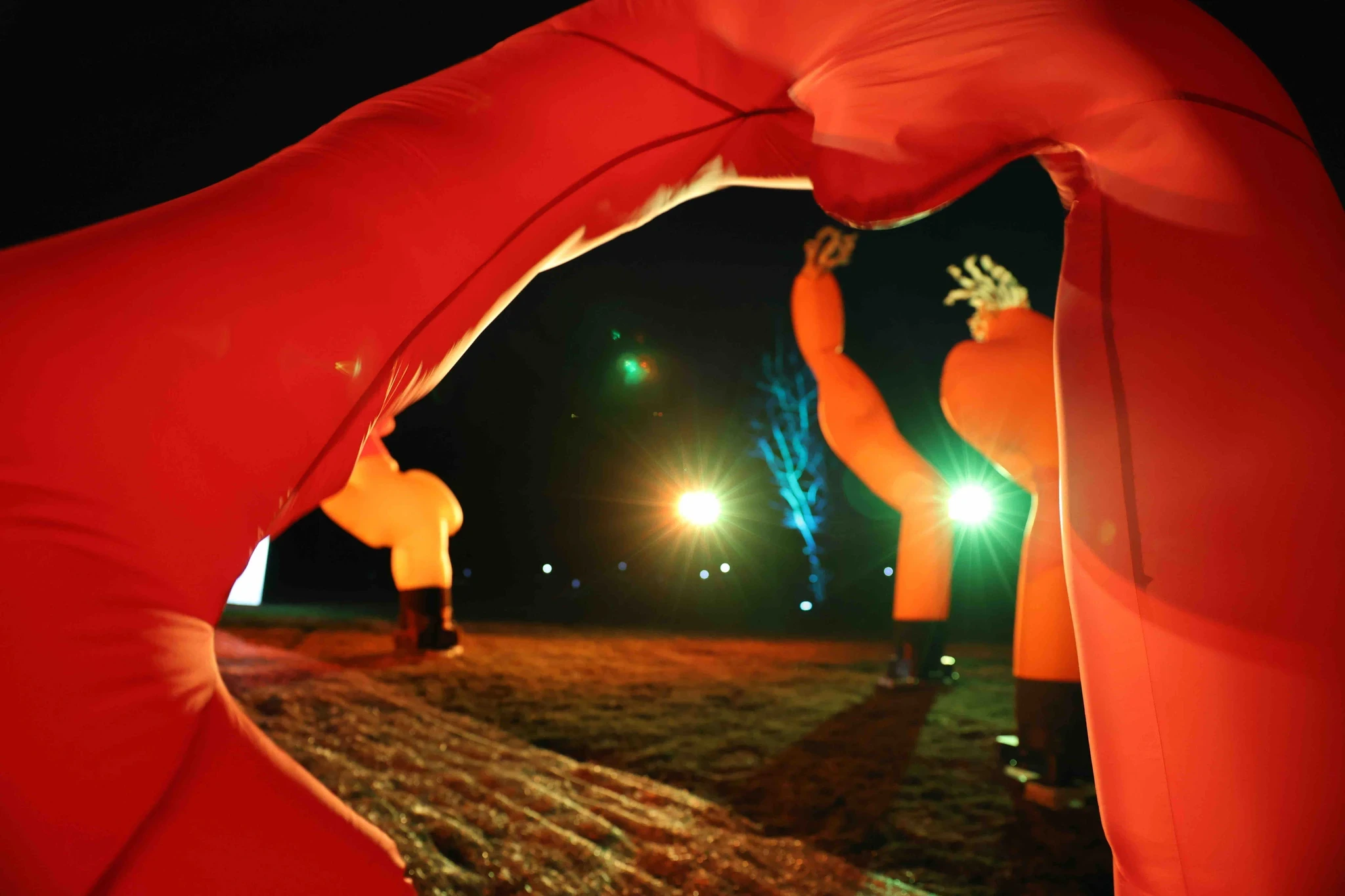 Two figures in red costumes create a dramatic scene with colored lights in the background.