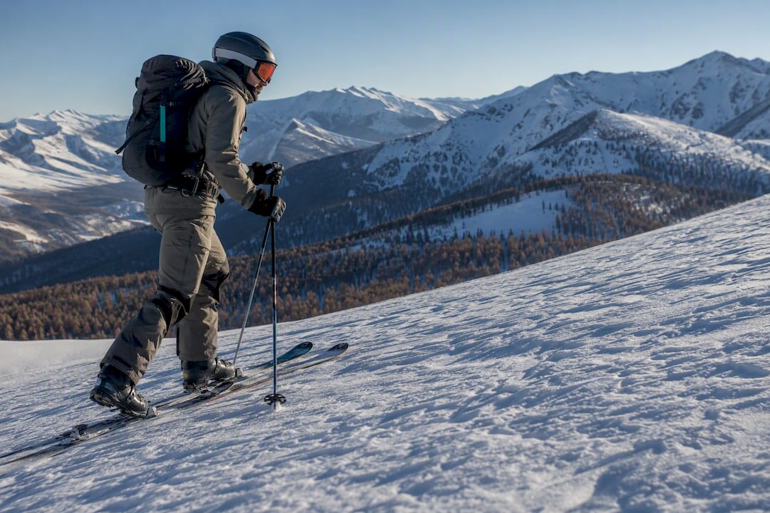 Skier skinning uphill on a snow-covered pass in the Western Altai