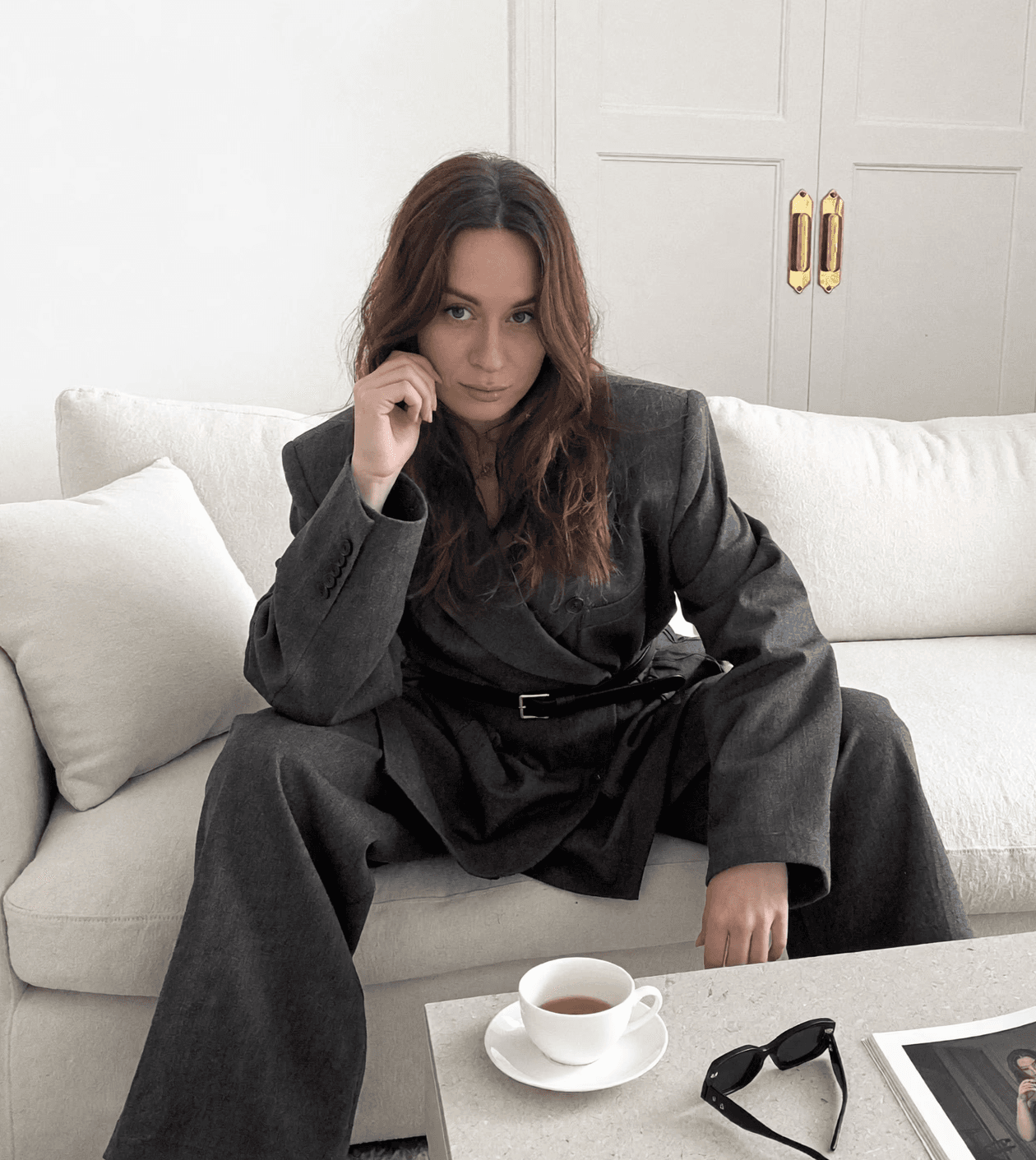 A stylish individual in a black shirt and silver pants stands against a blurred background, creating a dynamic and modern aesthetic.