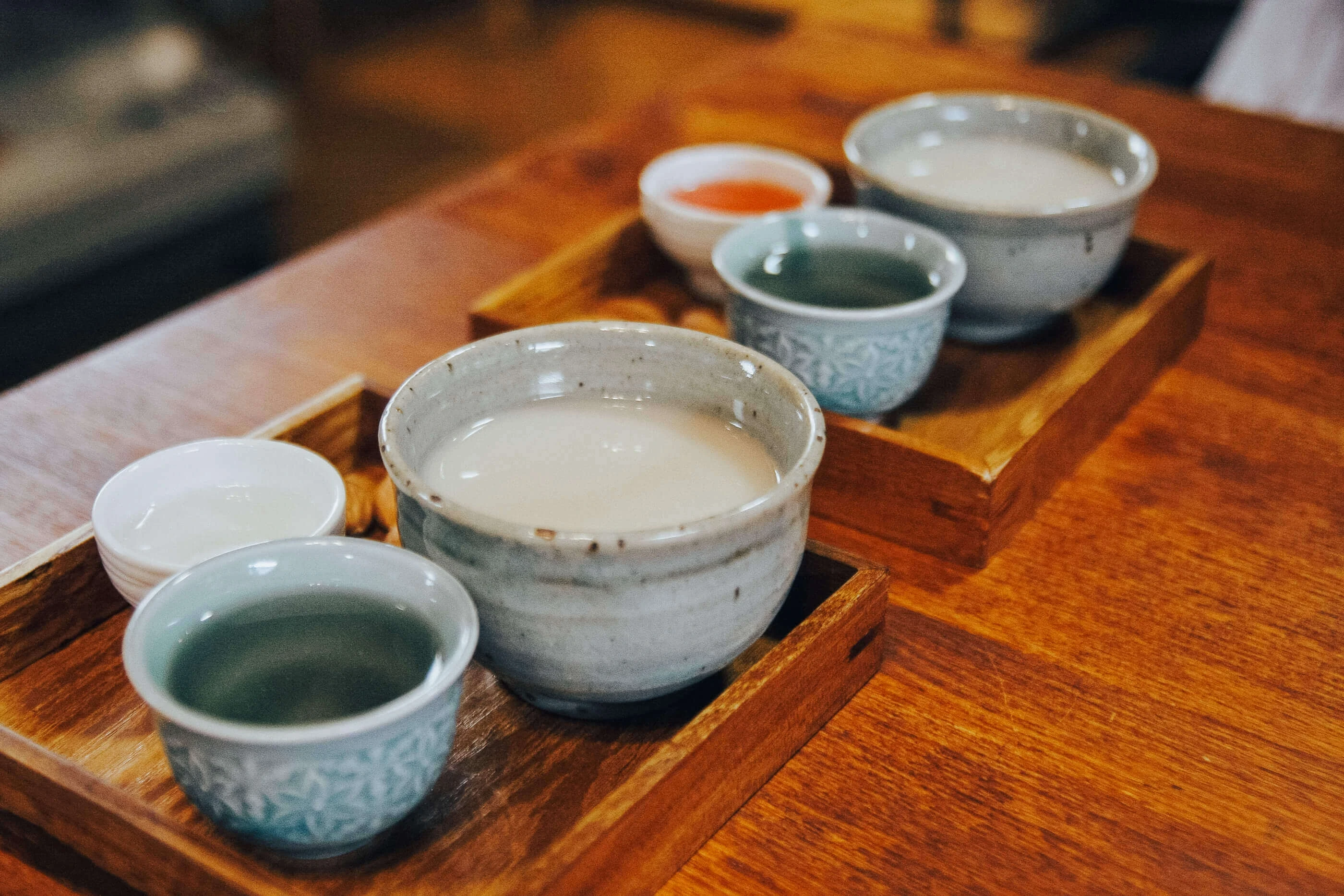 six ceramic cups filled with different types of asian (Korean) traditional liquor