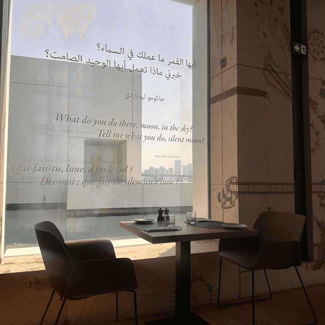 Cafe corner at Louvre Abu Dhabi by a large window overlooking the sea.