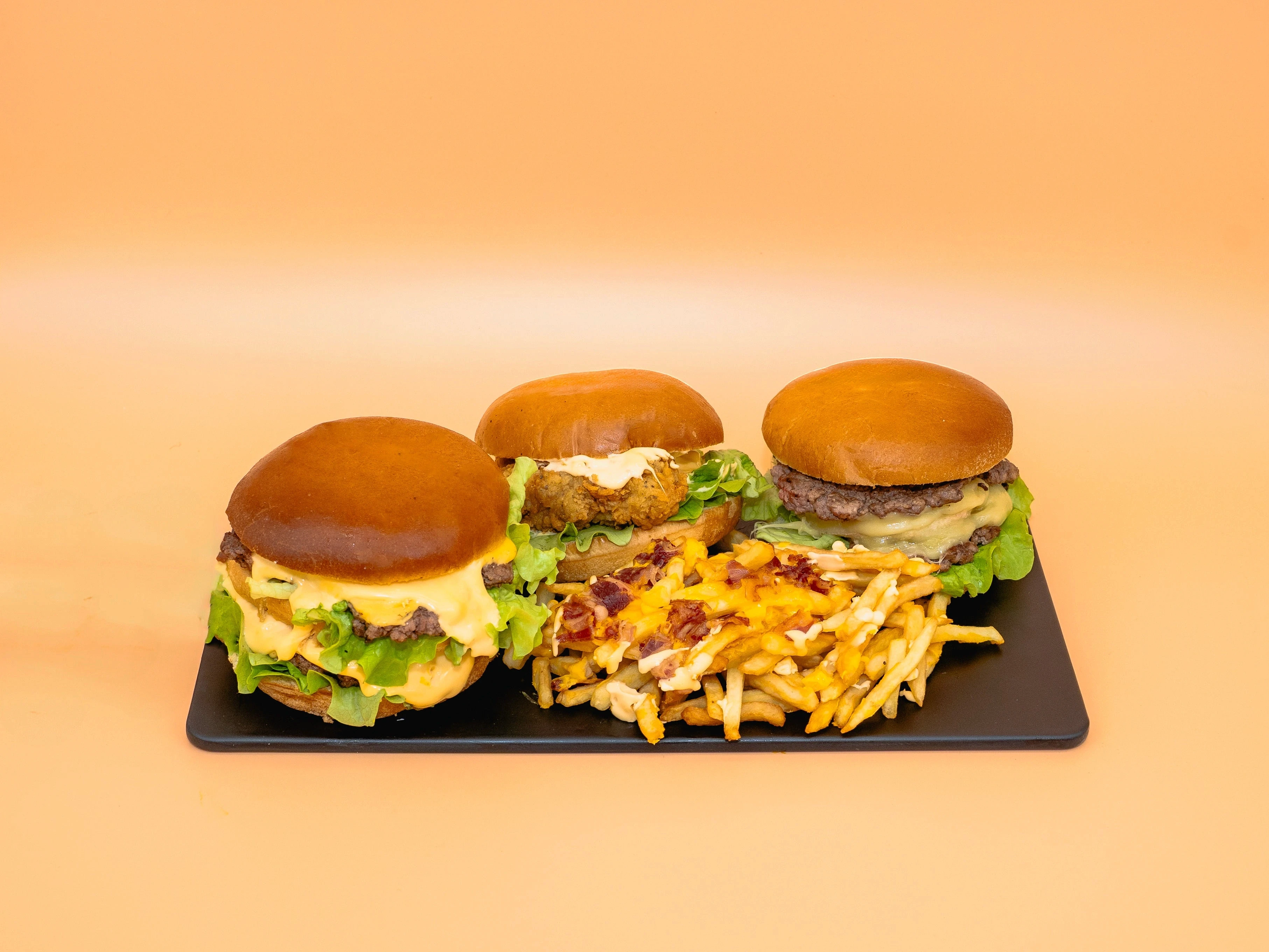 trois burgers sur un plateau avec des frites