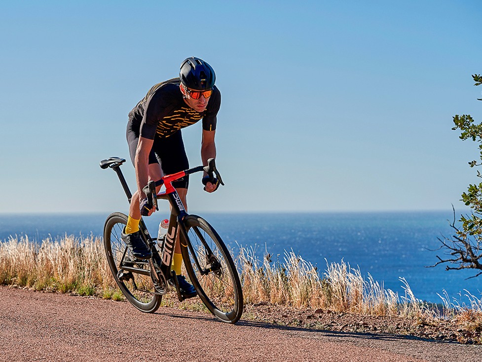 Photographie commerciale lifestyle casque de vélo homme en action devant la mer
