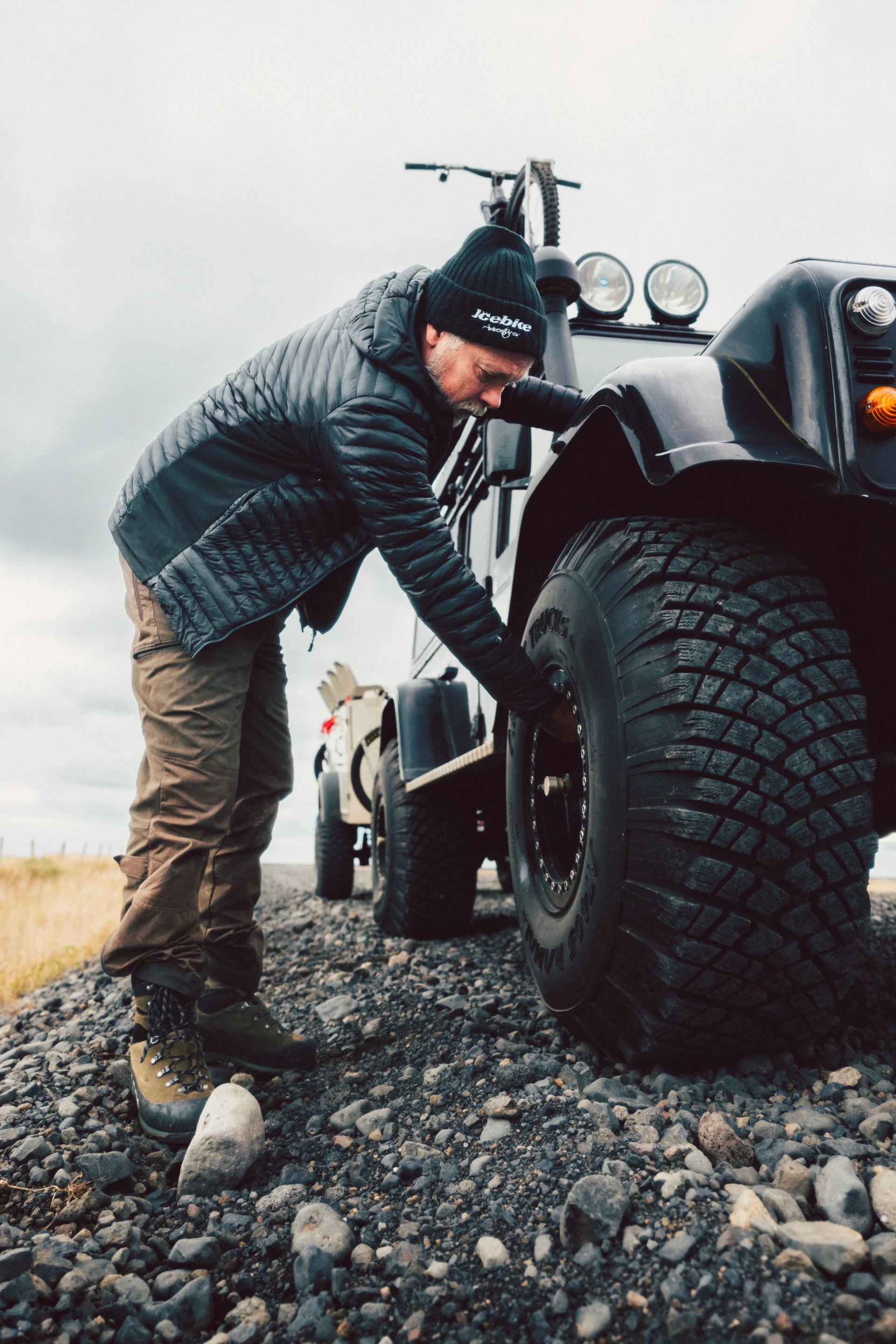 man fixes big tyre on superjeep in Iceland