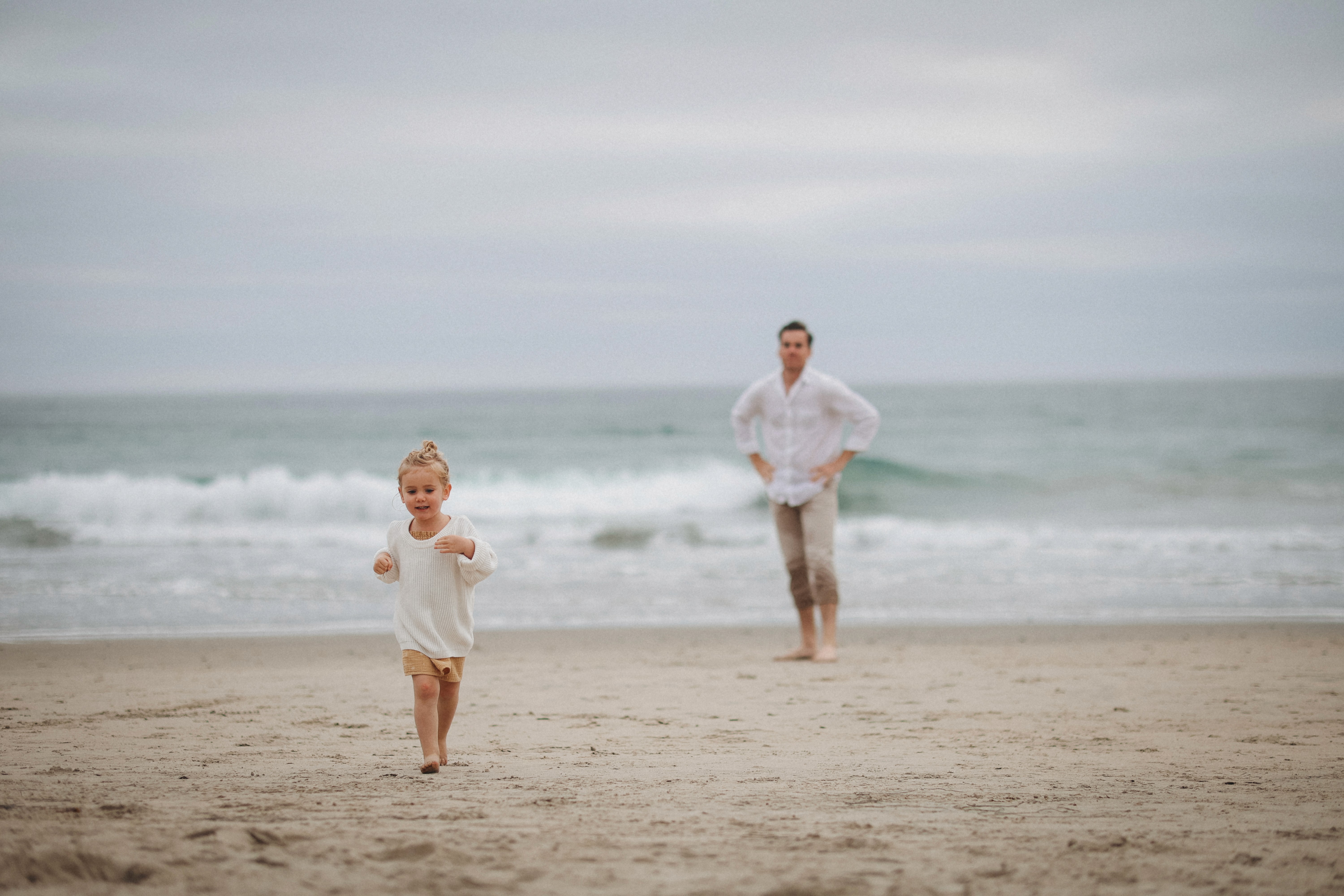 Children running by the ocean shoreline during a relaxed family session