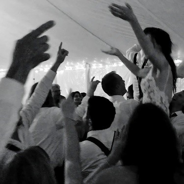 The bride and groom lifted high in the air by their friends and family, celebrating their joy and excitement during the wedding reception.