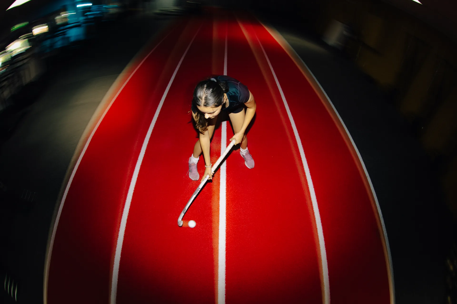 Hockeyspeler met stick op de rode sprintbaan van Strive