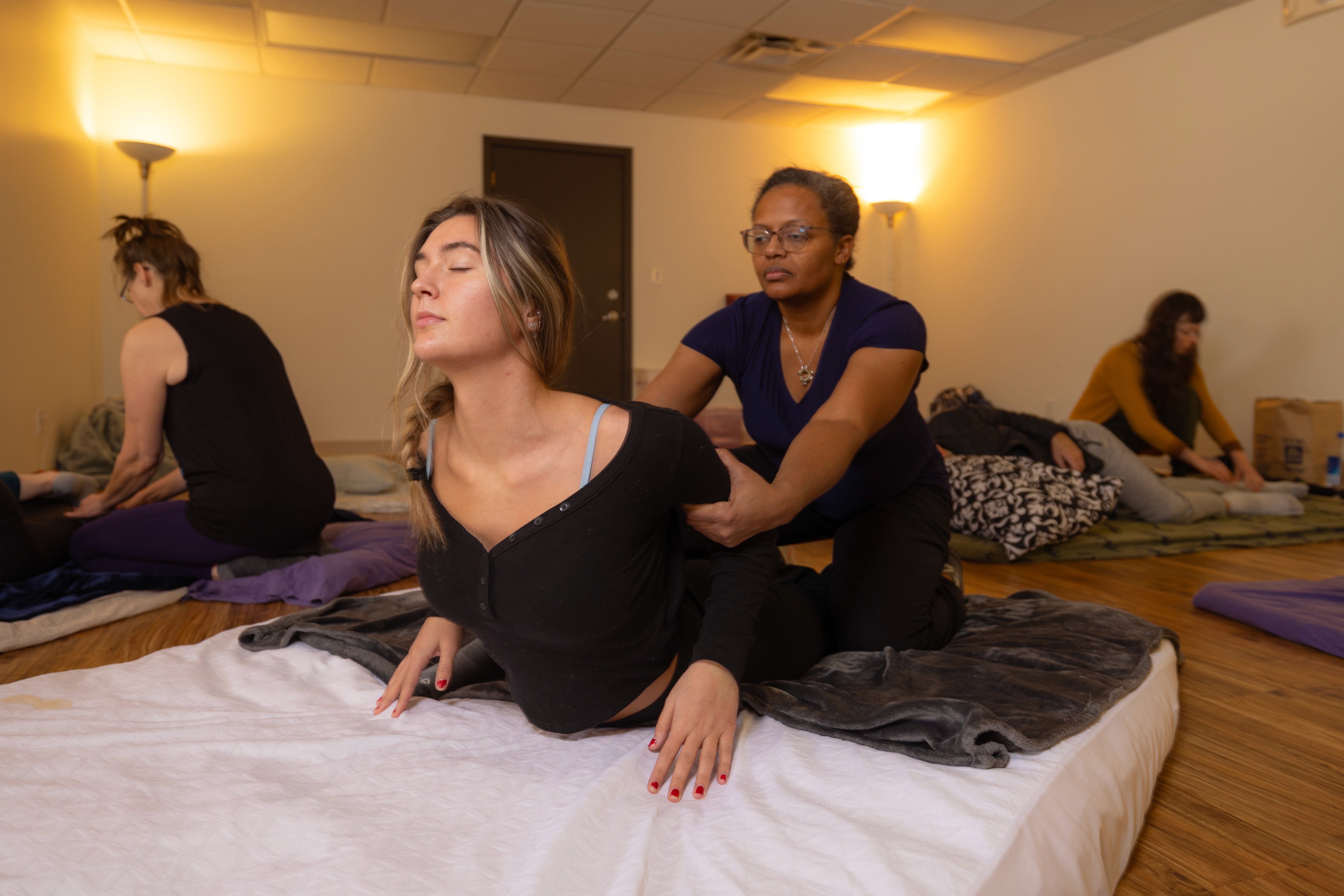 Massage therapy student performing assisted stretching technique under instructor supervision at Body Wisdom School.