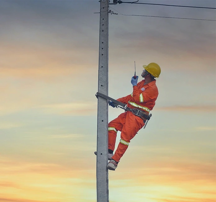 Worker climbing utility pole on job site, representing electrocution and fall risks