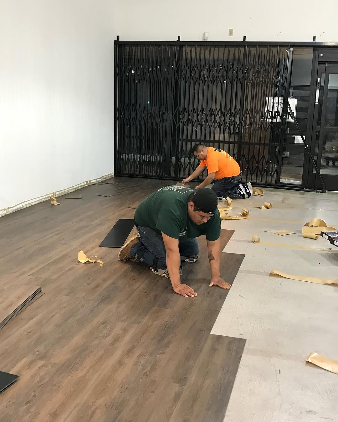 Installers laying floating luxury vinyl tile across a retail floor