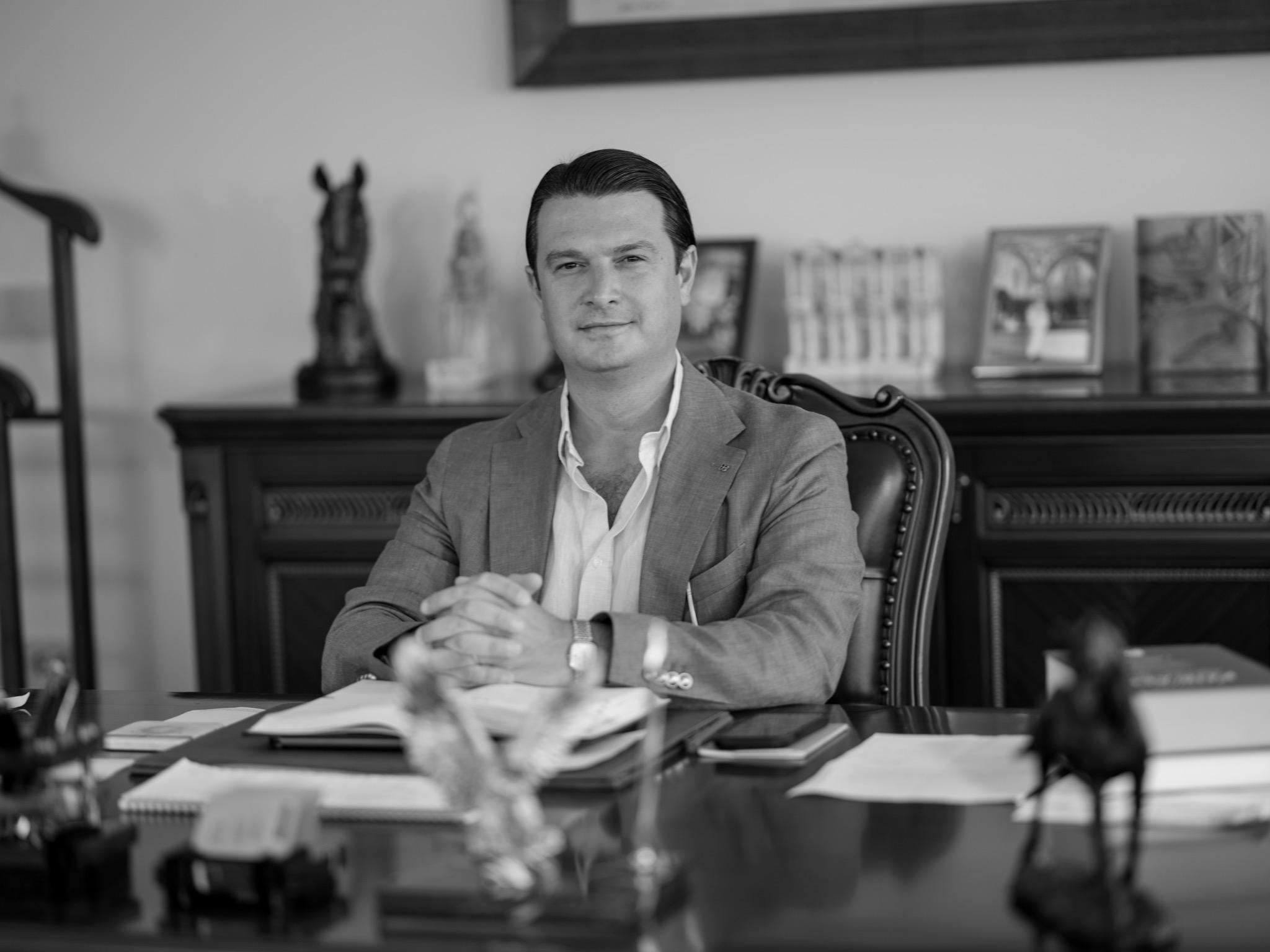 Collaborative work session overhead view of six people collaborating at a rustic wooden table with coffee, papers, and a laptop