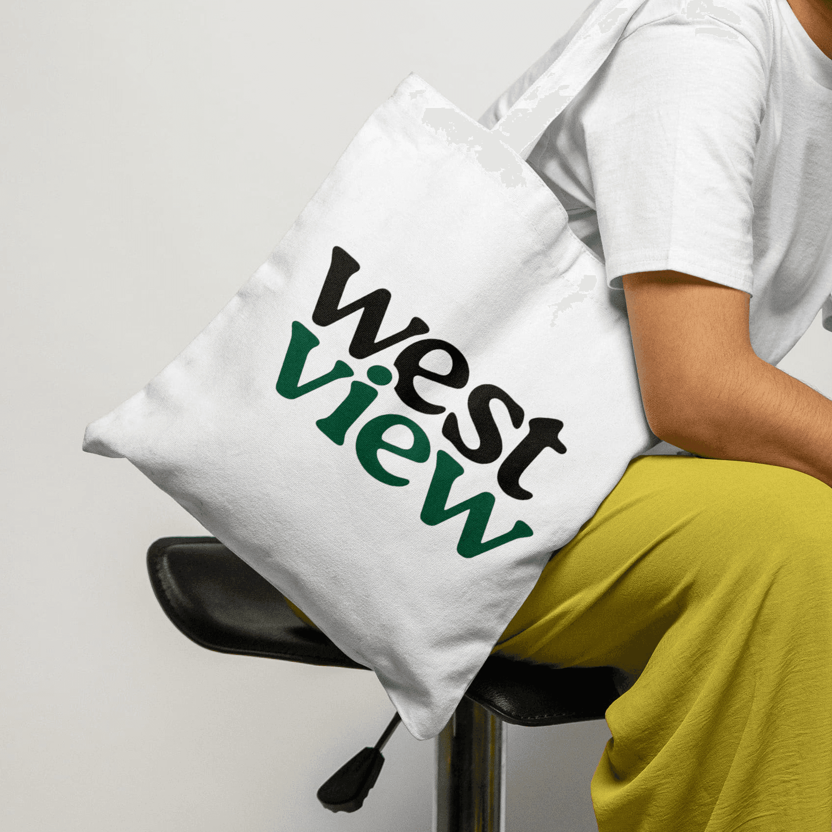 A woman wearing white tote bag with the Westview logo on it. Against a white backdrop.