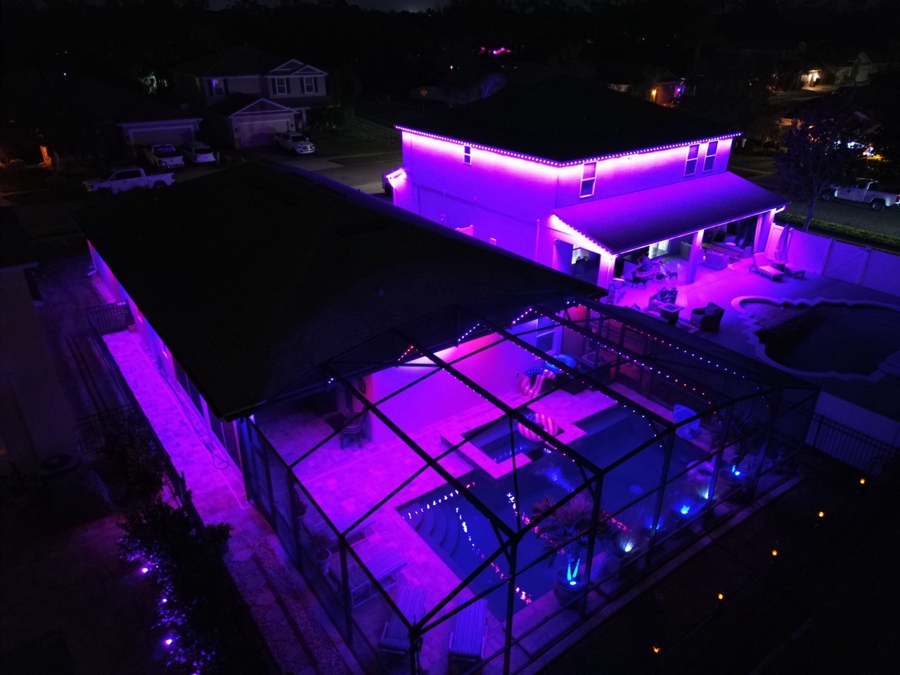 Custom color pool cage lighting illuminating backyard entertainment area