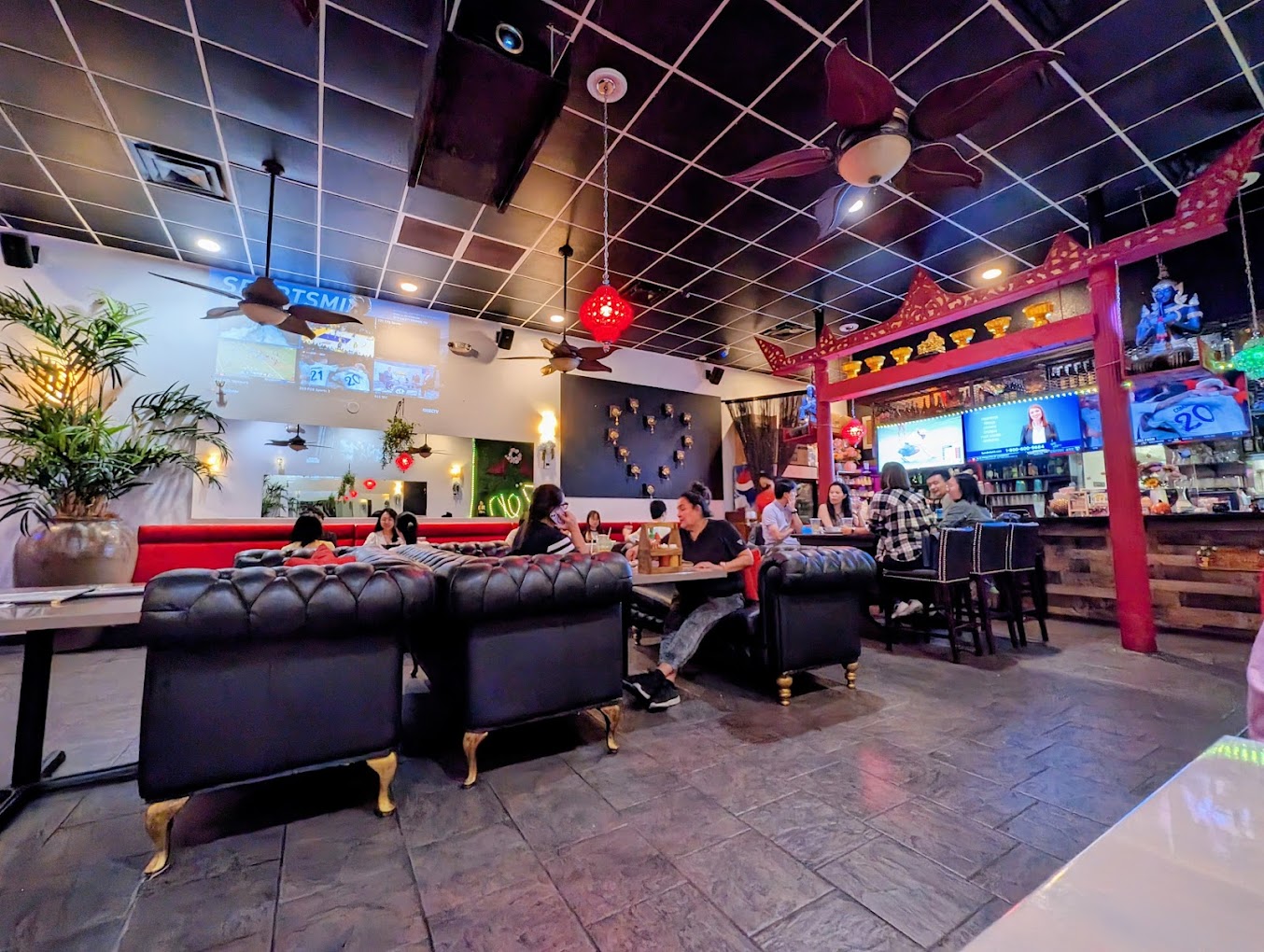 A restaurant scene with plush chairs, thai decorations, and a long dinner table