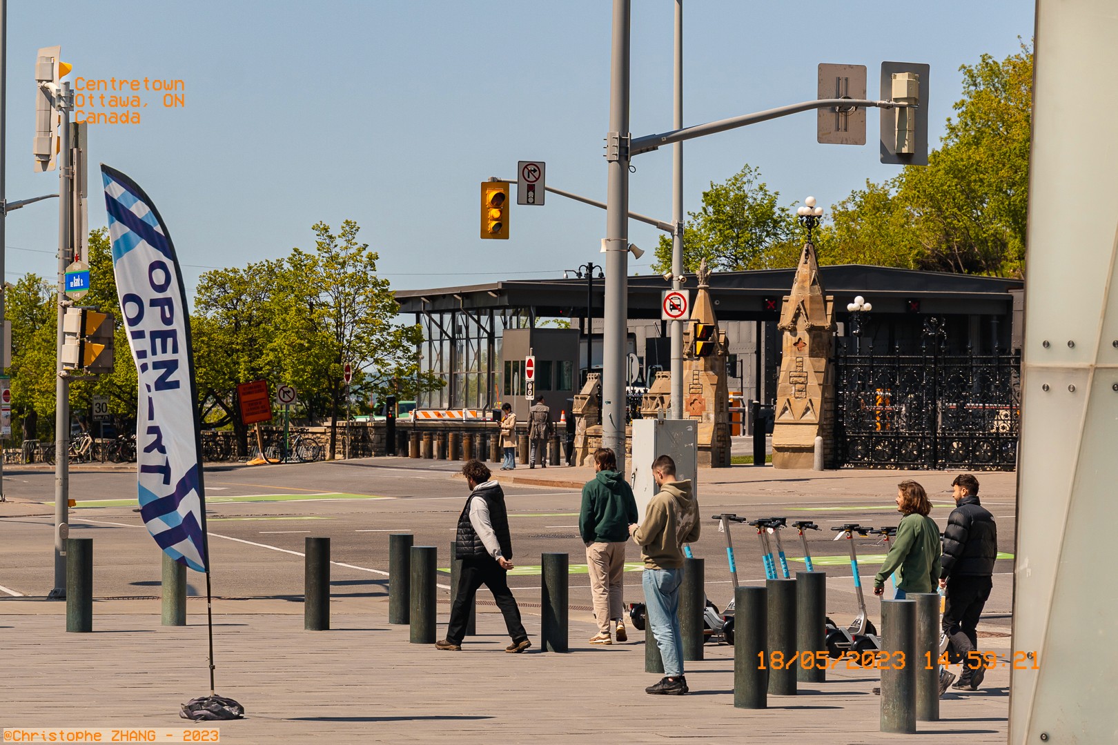 Scène urbaine à Ottawa avec des passants et des trottinettes électriques à un croisement.