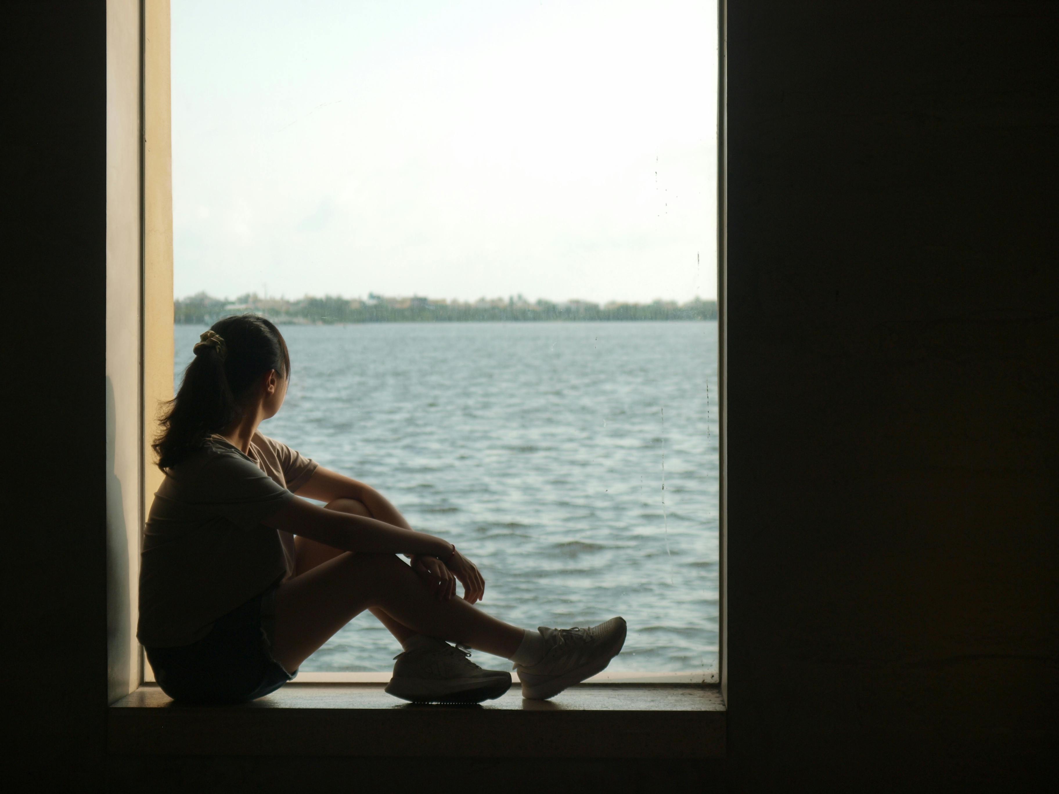 A woman daydreaming at the window looking at the ocean view