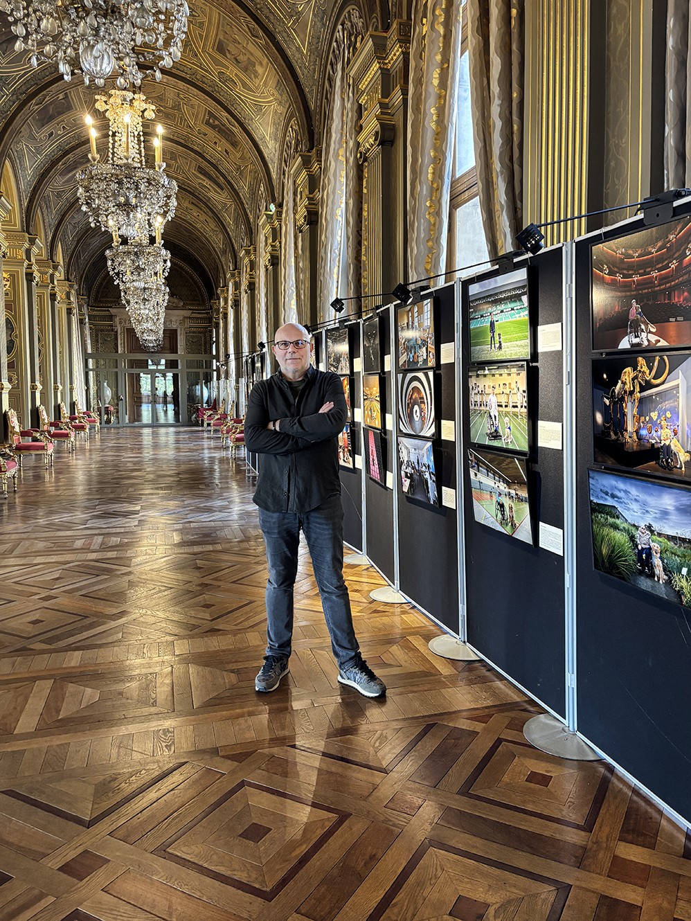 Frédéric Bourcier, photographe documentaire, avec sa fille devant une série de portraits en noir et blanc exposés sur les murs d’une galerie.