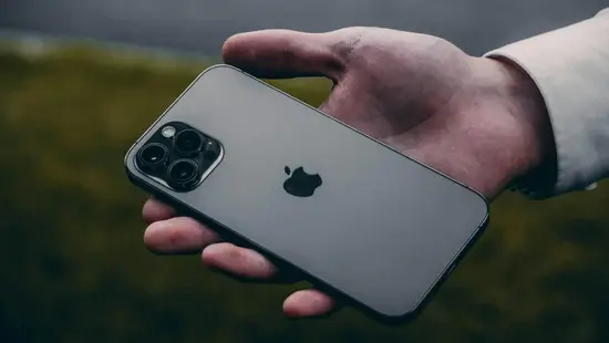 Back view of a triple-camera Apple iPhone Pro held in hand