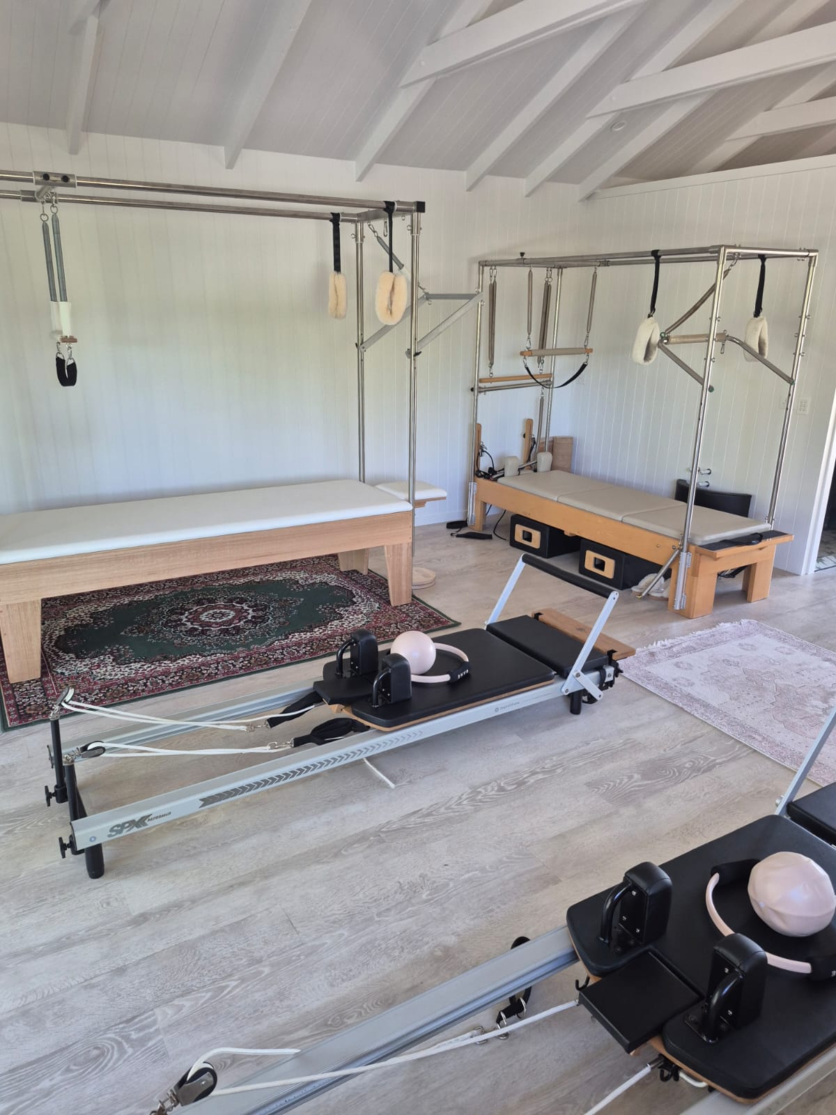 Pilates Cadillac and ladder barrel setup in peaceful studio with warm wooden tones.