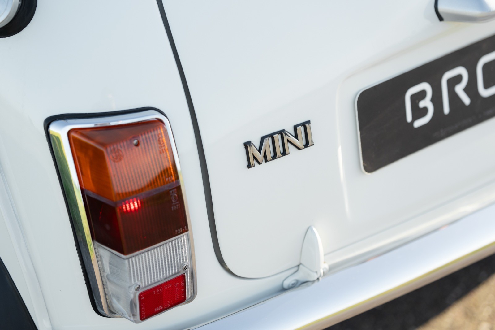 Close-up of a white vehicle's rear, highlighting the taillight and the brand logo.